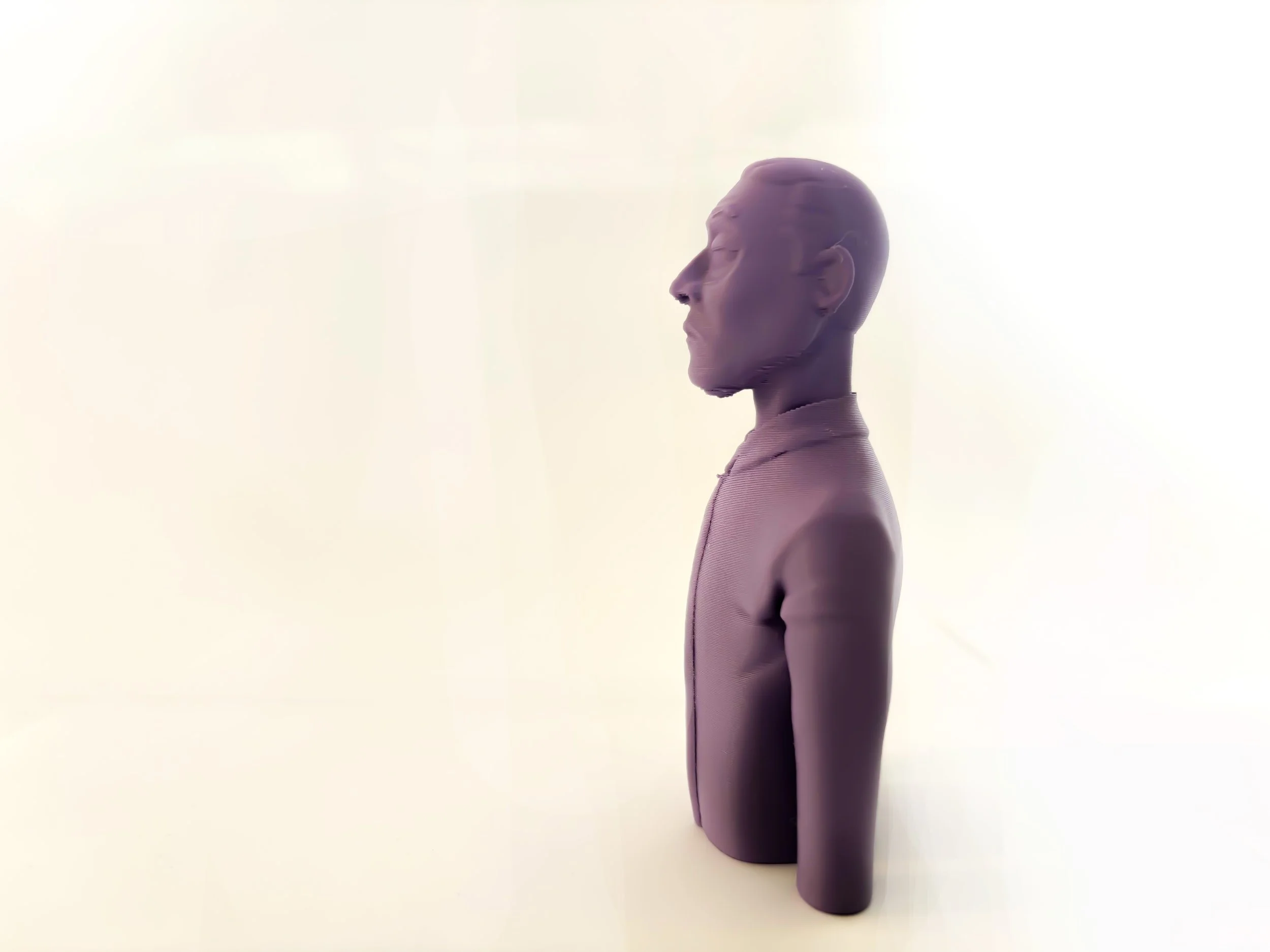 Purple 3D-Printed purple mannequin head and torso with closed eyes, facing left, against a cream-colored background.