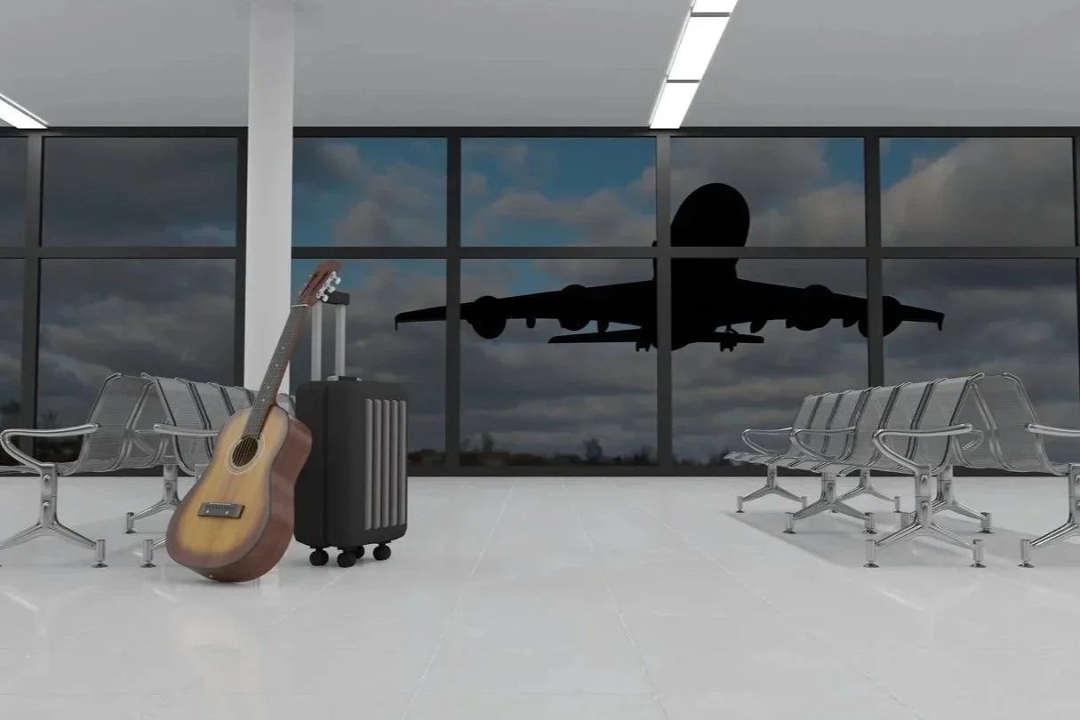 guitar and suitcase in airpport waiting area with airplane background