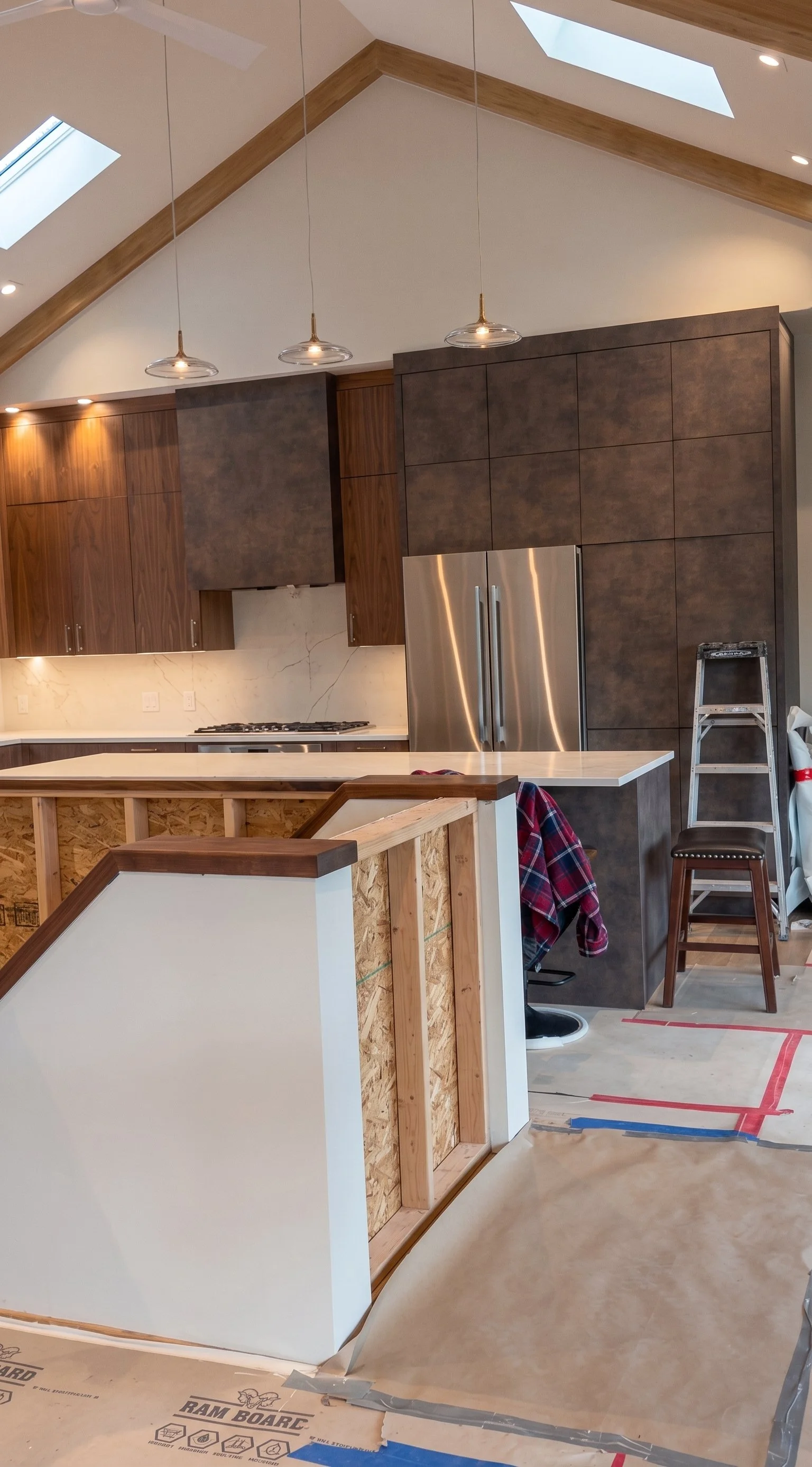 Ongoing post-construction cleanup in a modern kitchen with a stainless steel refrigerator, wooden cabinetry, and construction materials.