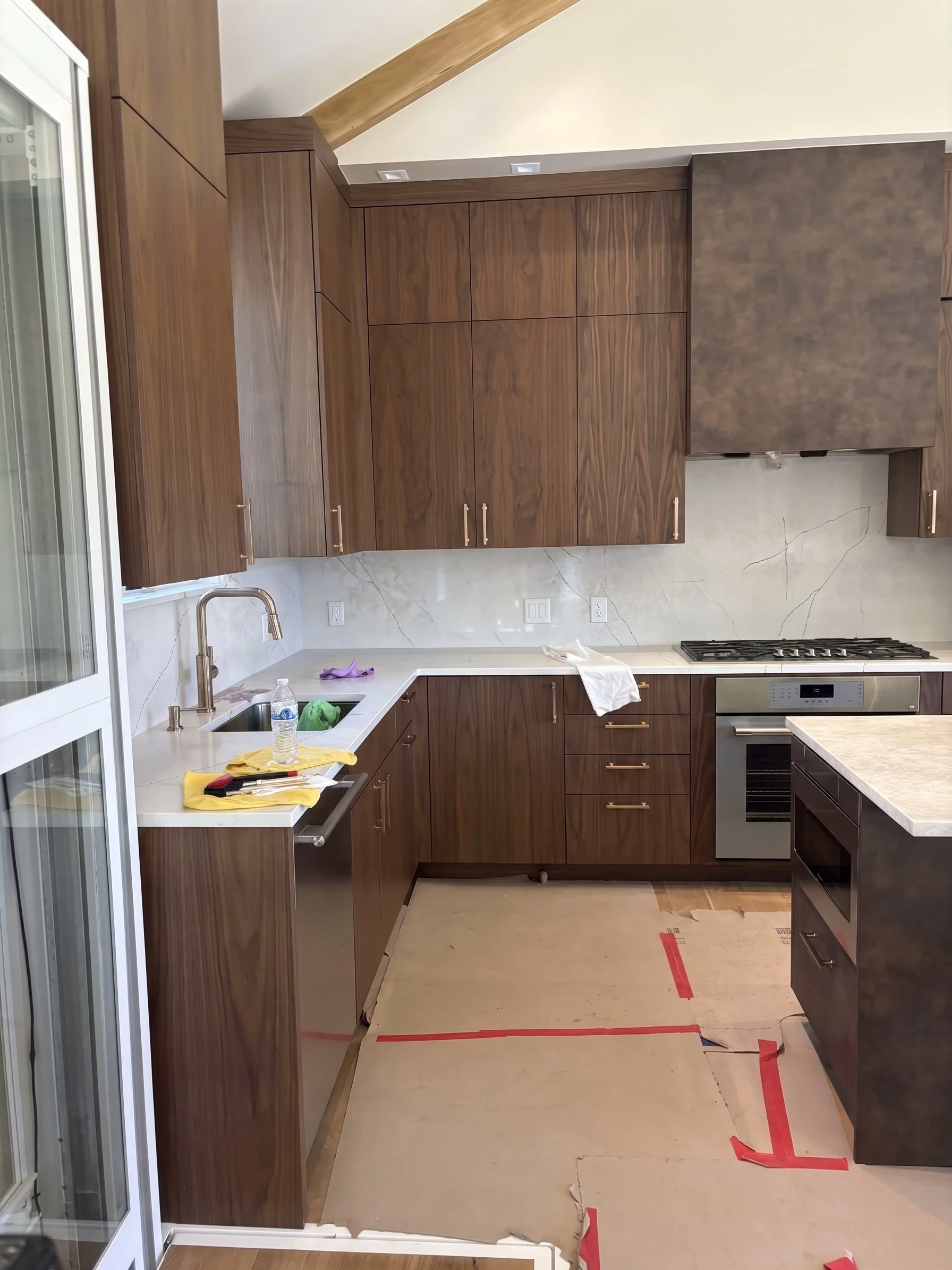 Post-construction kitchen cleaning services by VP Cleaning Services, showing wooden cabinets, marble backsplash, and protected flooring.