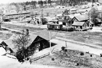 A black and white photo of a historic neighborhood with houses, trees, and a street with power lines.