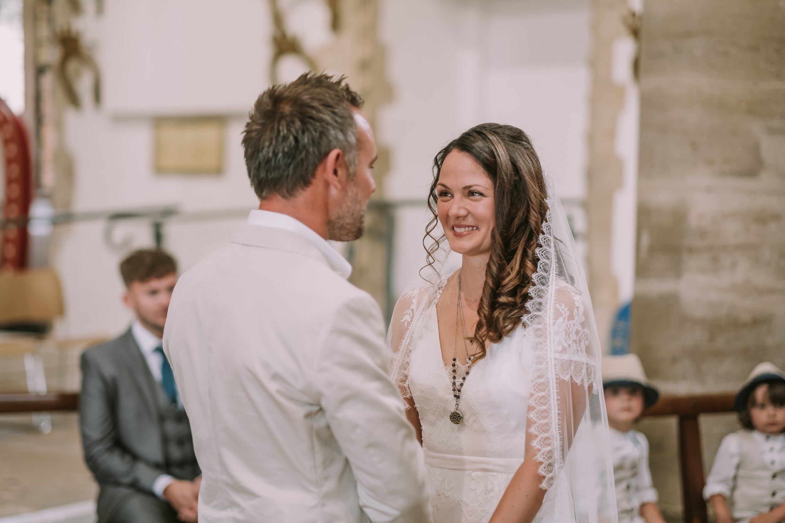 A wedding ceremony with a couple exchanging vows, surrounded by guests seated in a church or chapel setting.