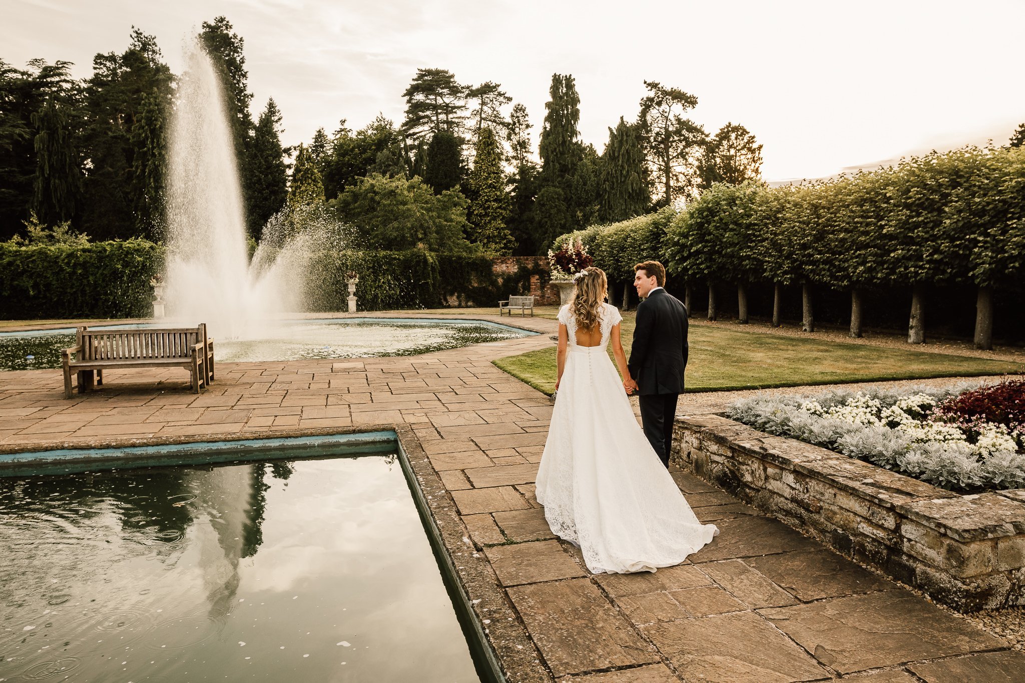  Bride and Groom walking next to the water fountain at Arley House and Gardens 