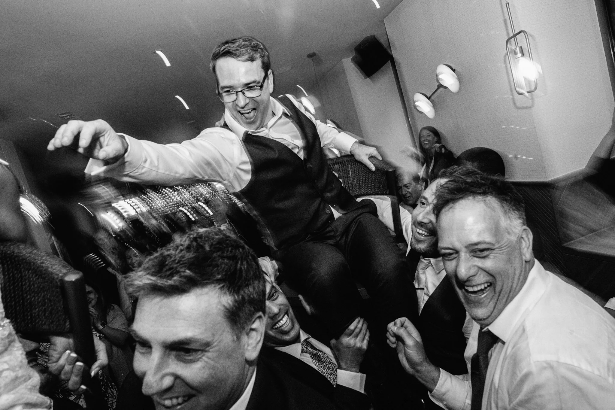  The groom is being lifted up whilst sitting on a chair. 