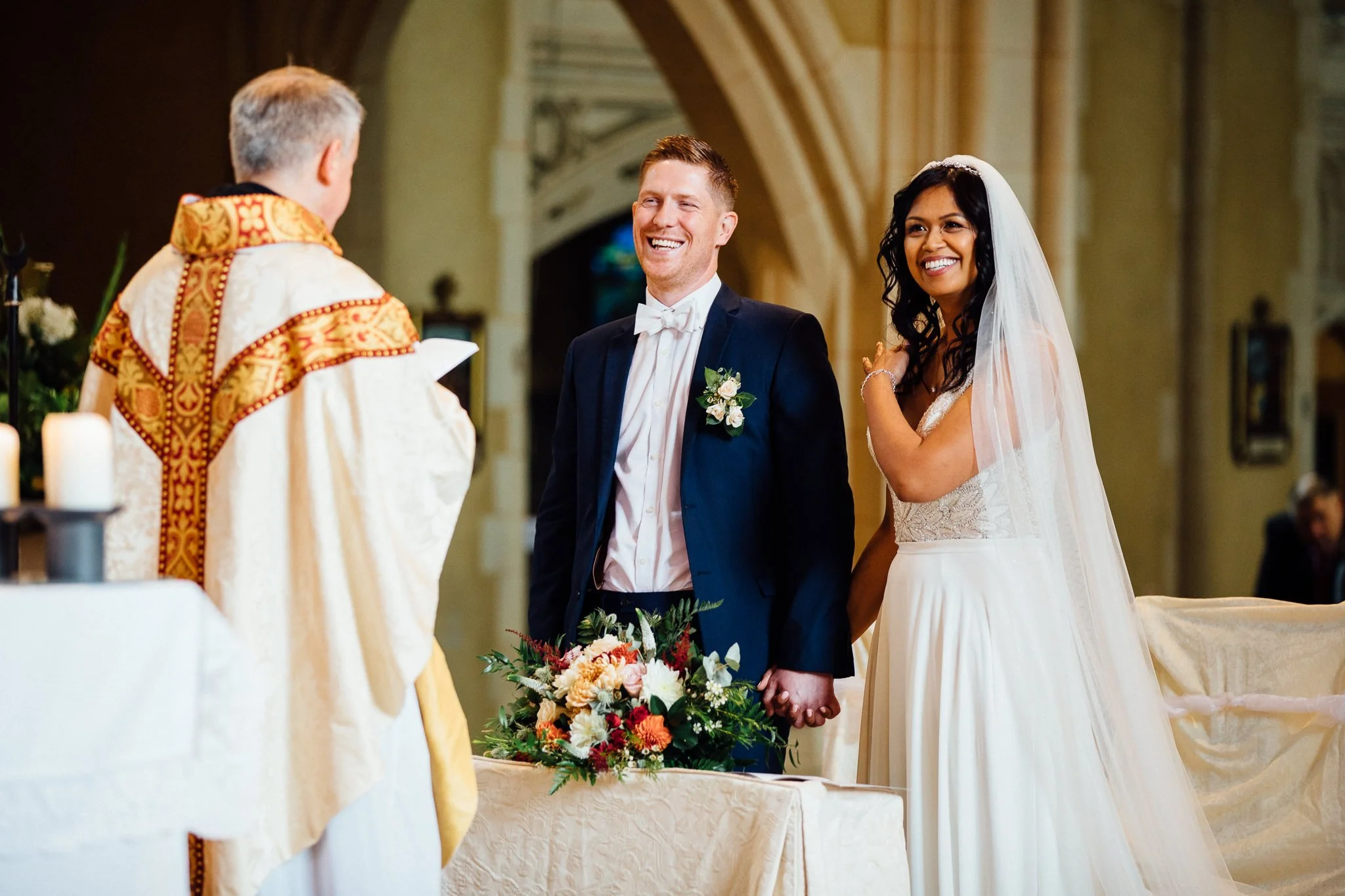  Bride and Groom smiling during the ceremony at Ealing Abbey 