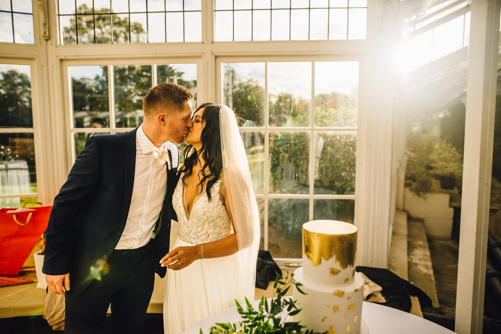  Bride and Groom kiss in front of the wedding cake at Chiswick House and Gardens 