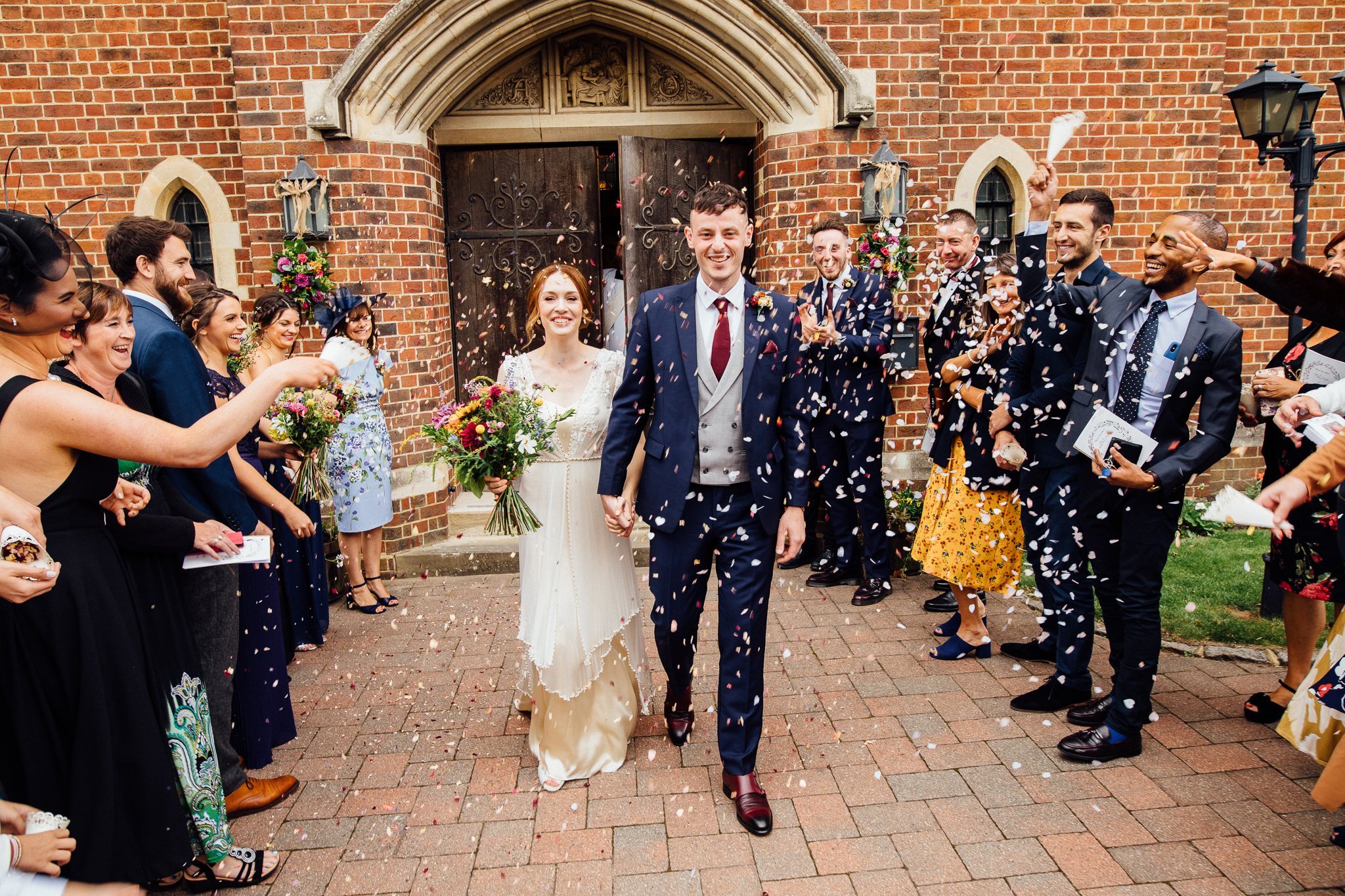  Bride and groom have confetti thrown at them outside the The Holy Family Church in Reigate 