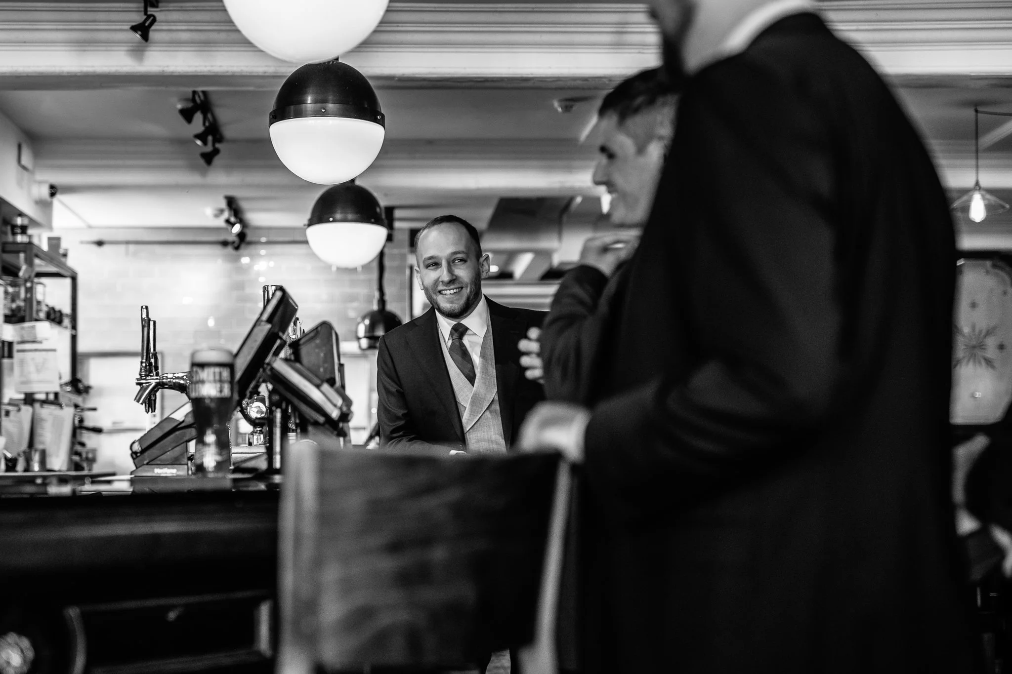  Groom leaning on the bar and smiling 