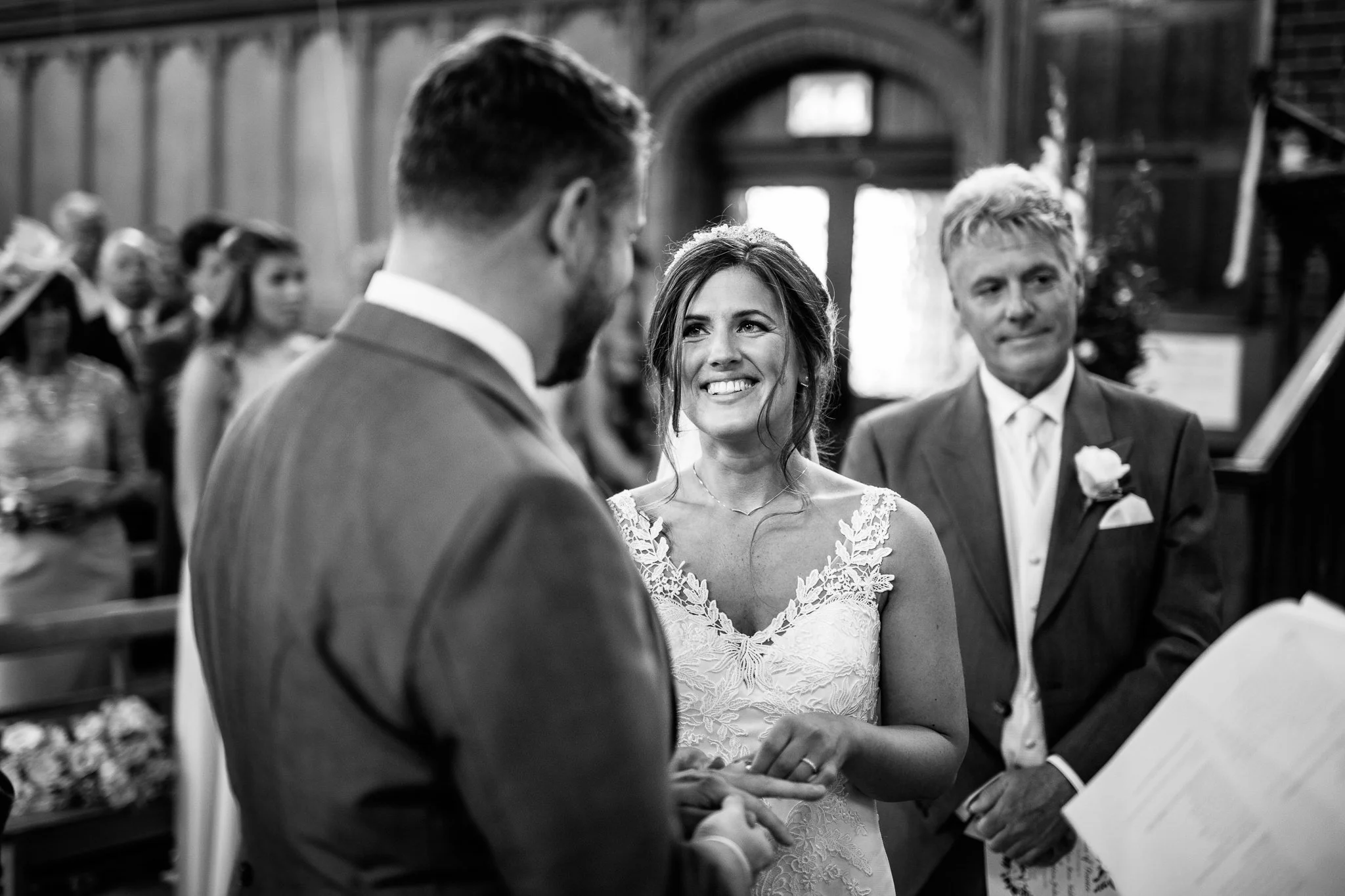  Bride puts a wedding ring on the Groom  at the Chapel of St Luke at Epsom College 