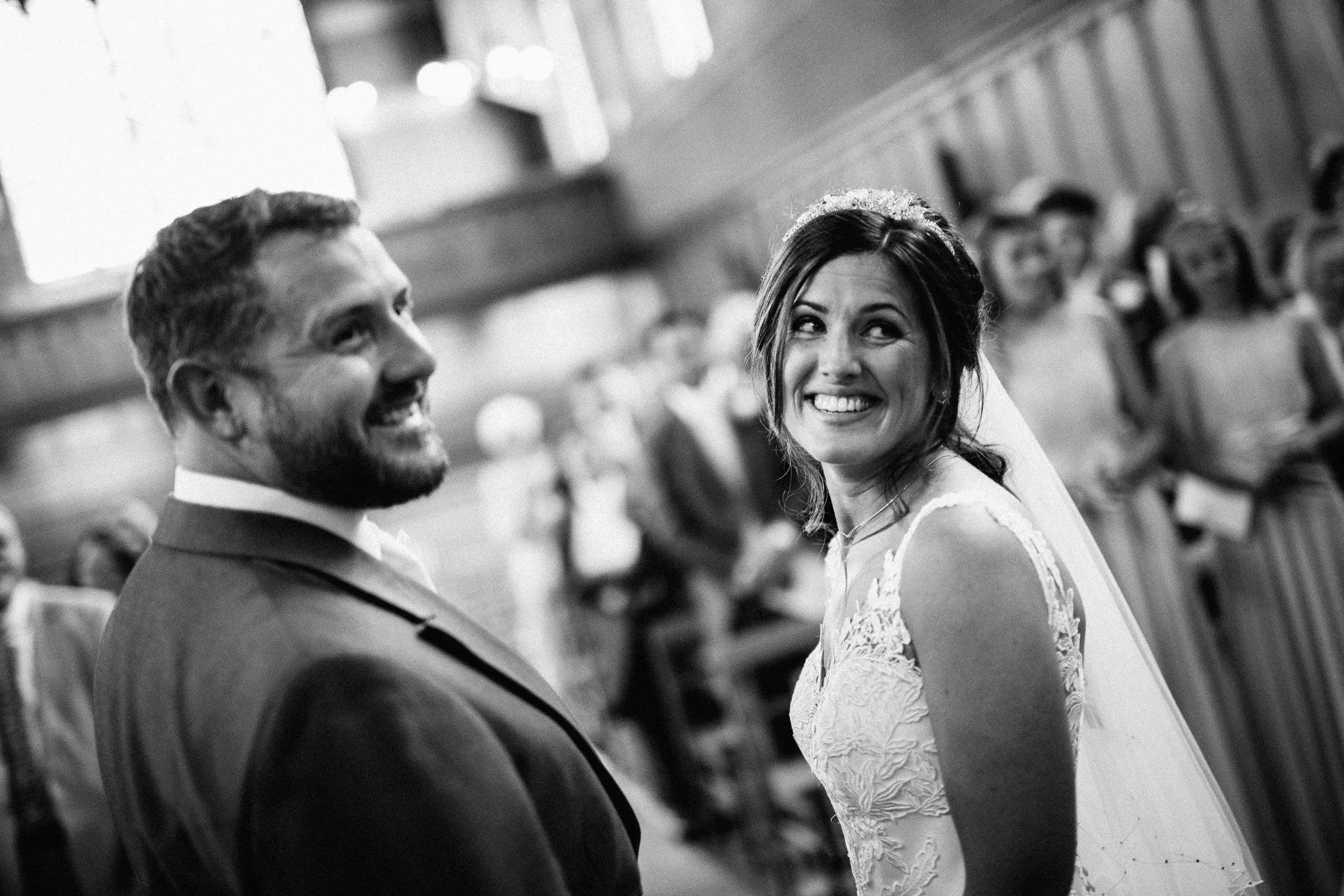  Bride and Groom look over their shoulders  at the Chapel of St Luke at Epsom College 