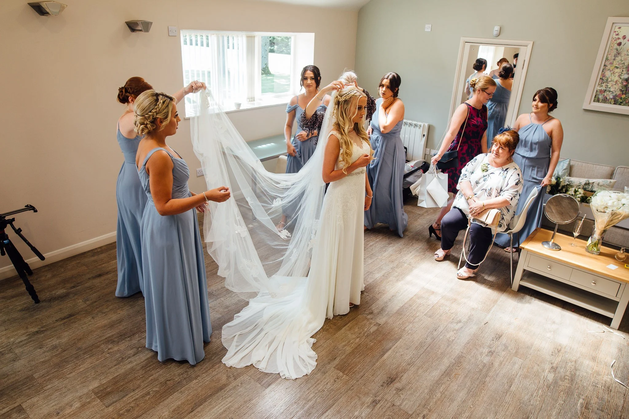  The Bride has her veil held aloft by a Bridesmaid 
