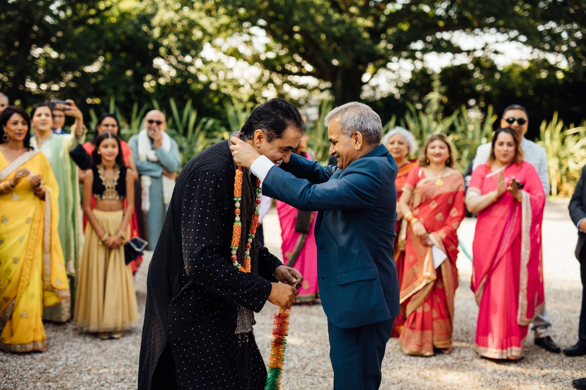  Man puts garland of flowers around another mans neck 