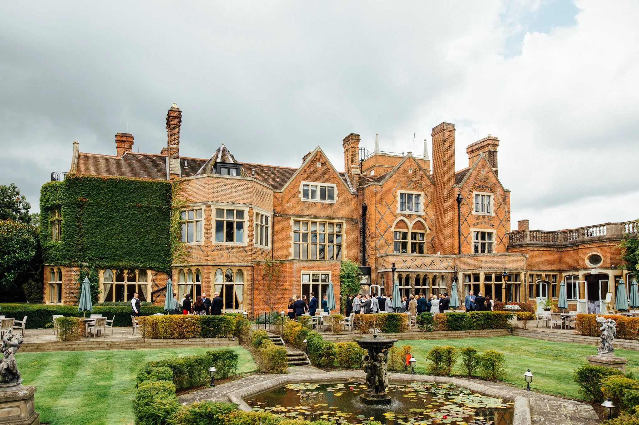  Wedding guests standing in the gardens of Warren House Hotel Kingston upon Thames 