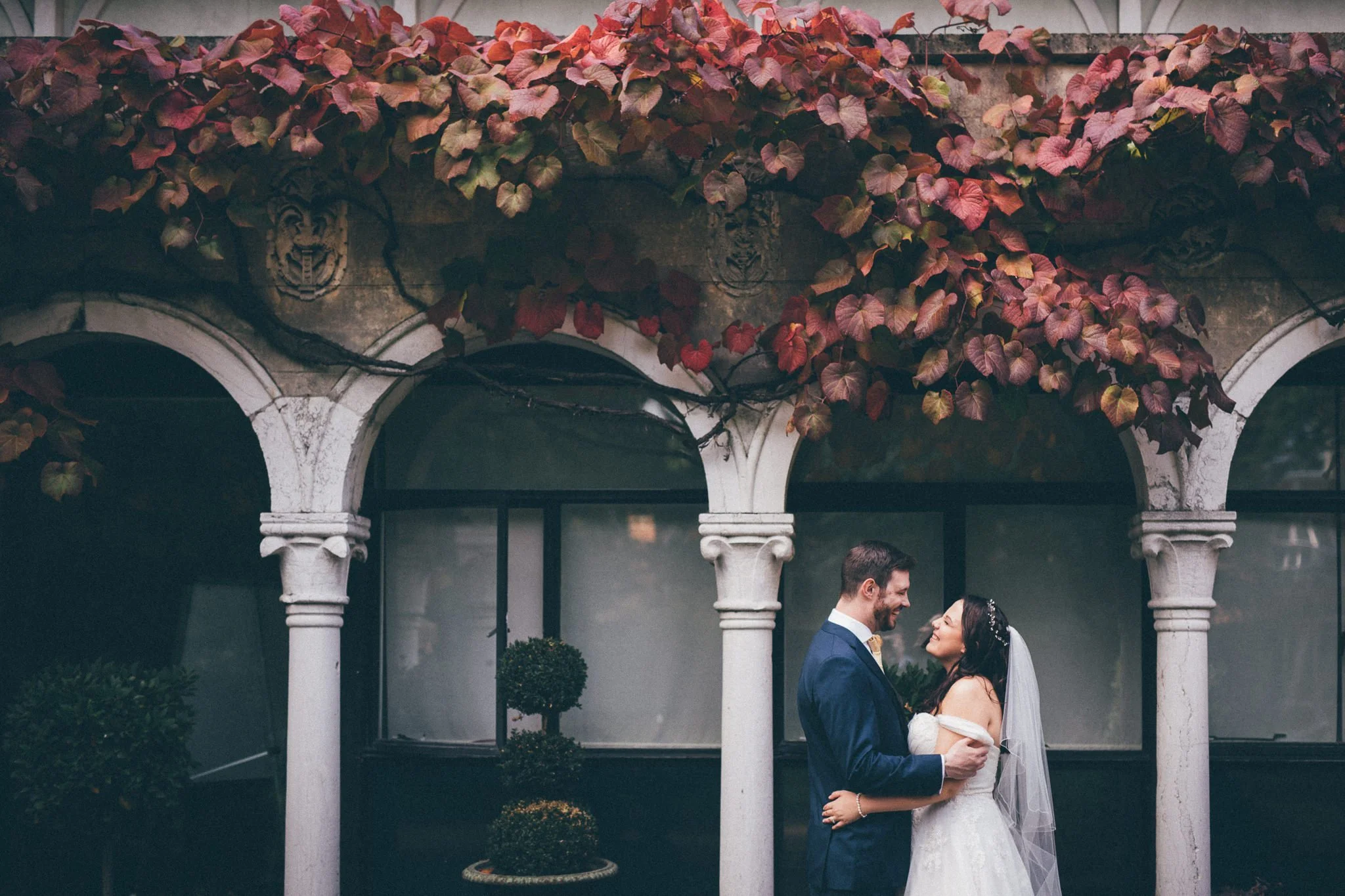  Bride and Groom laugh under an archway at Warren House Hotel Kingston upon Thames 
