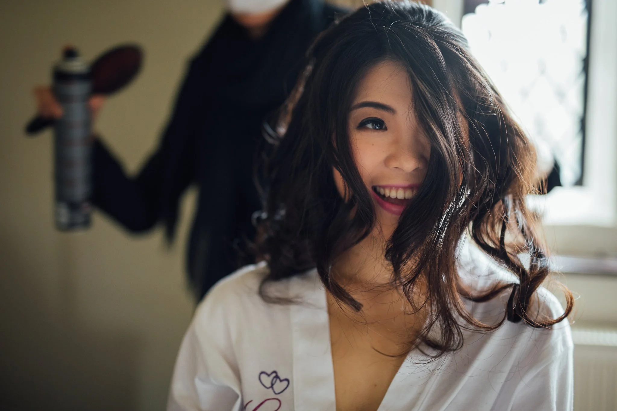  Bride’s hair falls in front of her face whilst the make up artist applies hairspray 