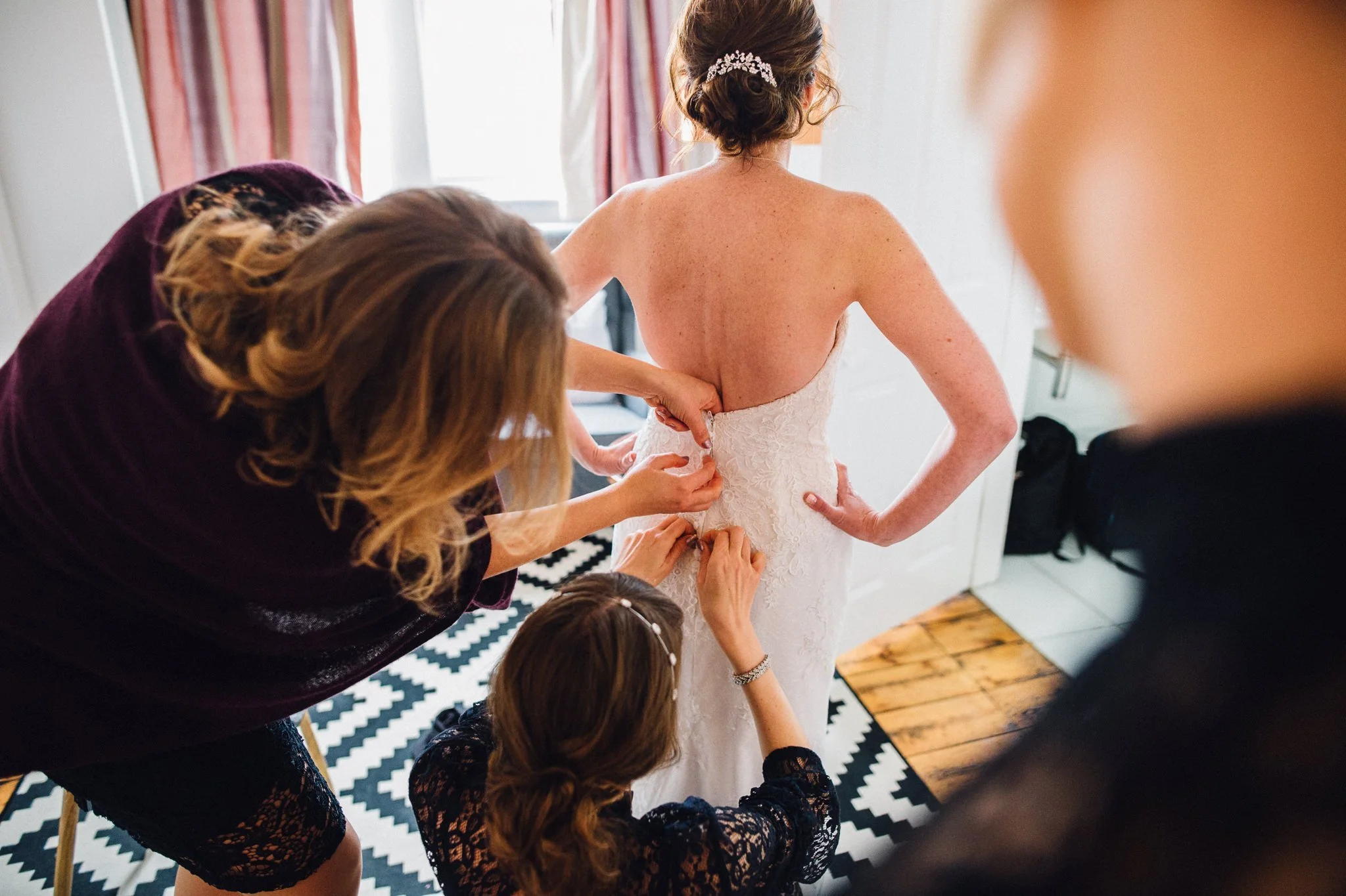  Bride has the back of her dress done up on her wedding day 