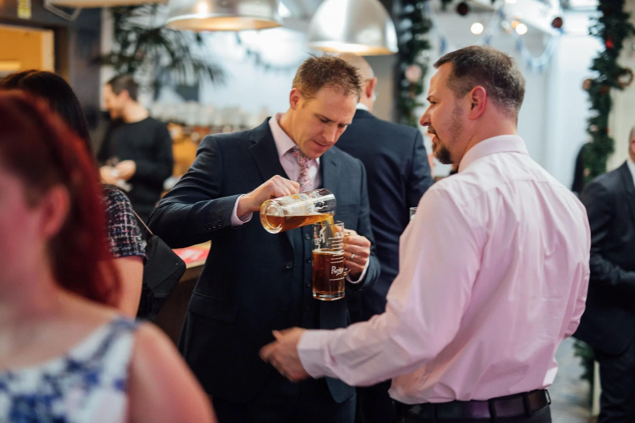  Wedding guest pouring beer from one glass to another 