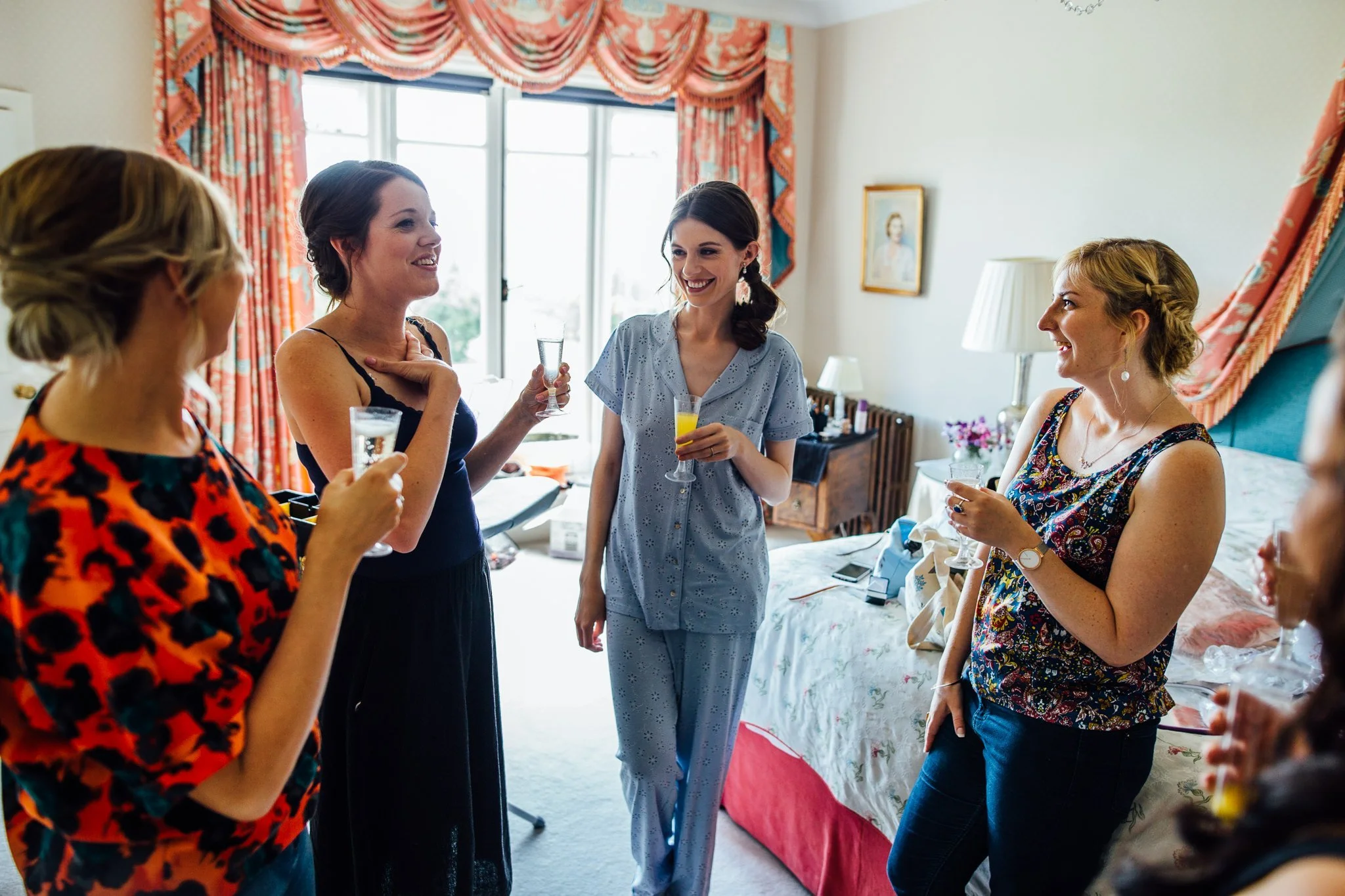  Bride and friends laughing during bridal preparation at  Wadhurst castle wedding venue 