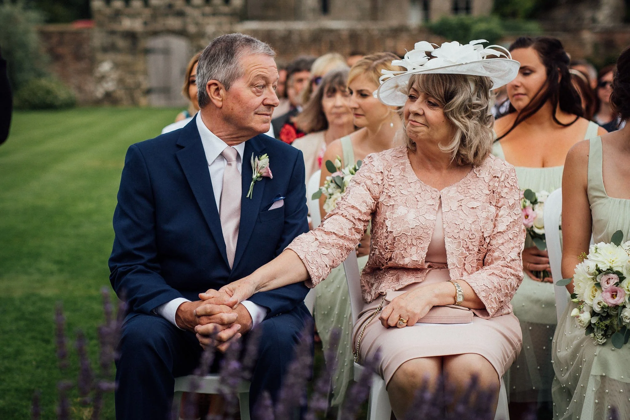  Mother of the bride holds her husnabn’s hand during the ceremony 