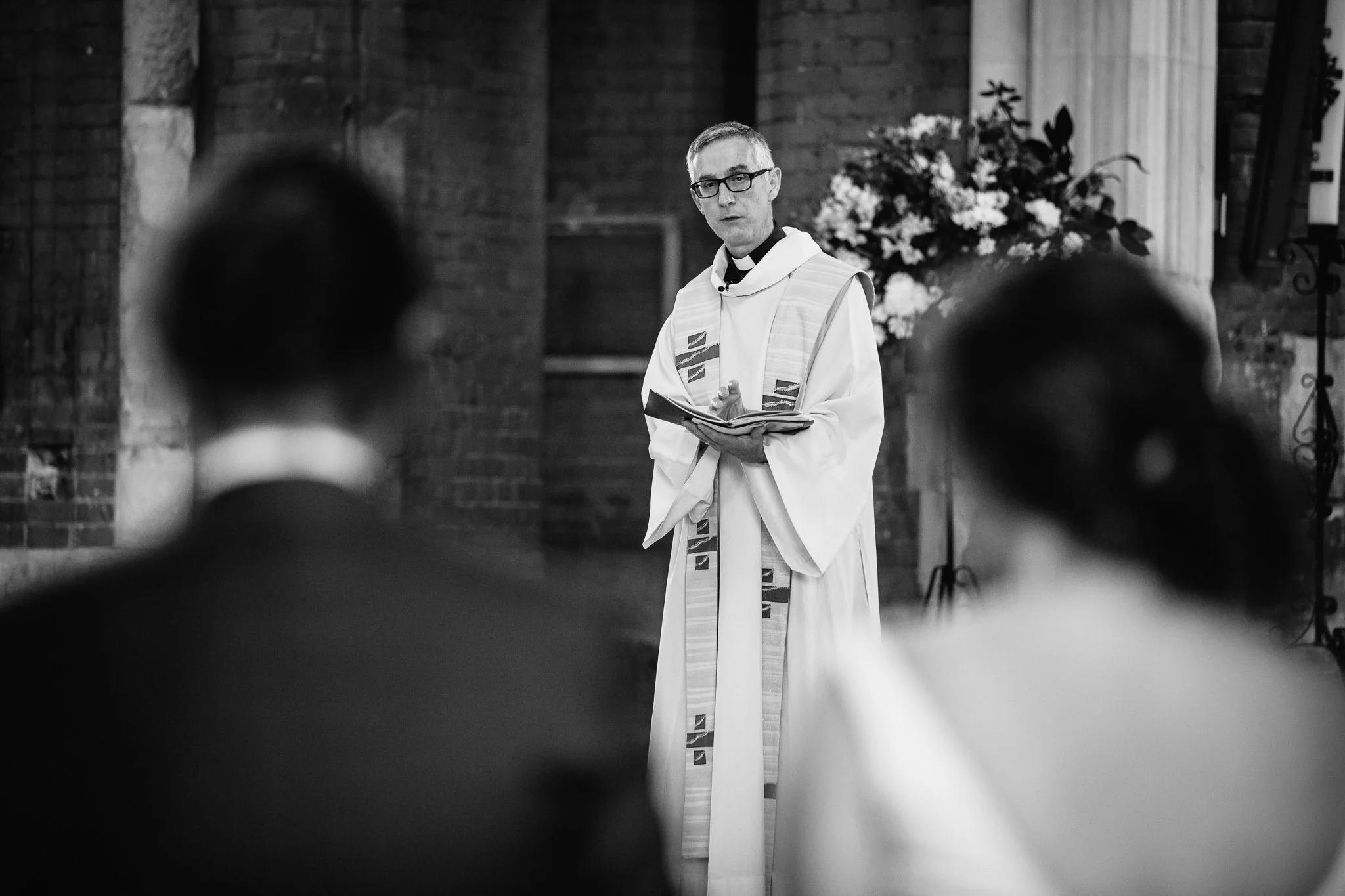  Vicar addresses the wedding guests at Inside of All Saints West Dulwich Church 
