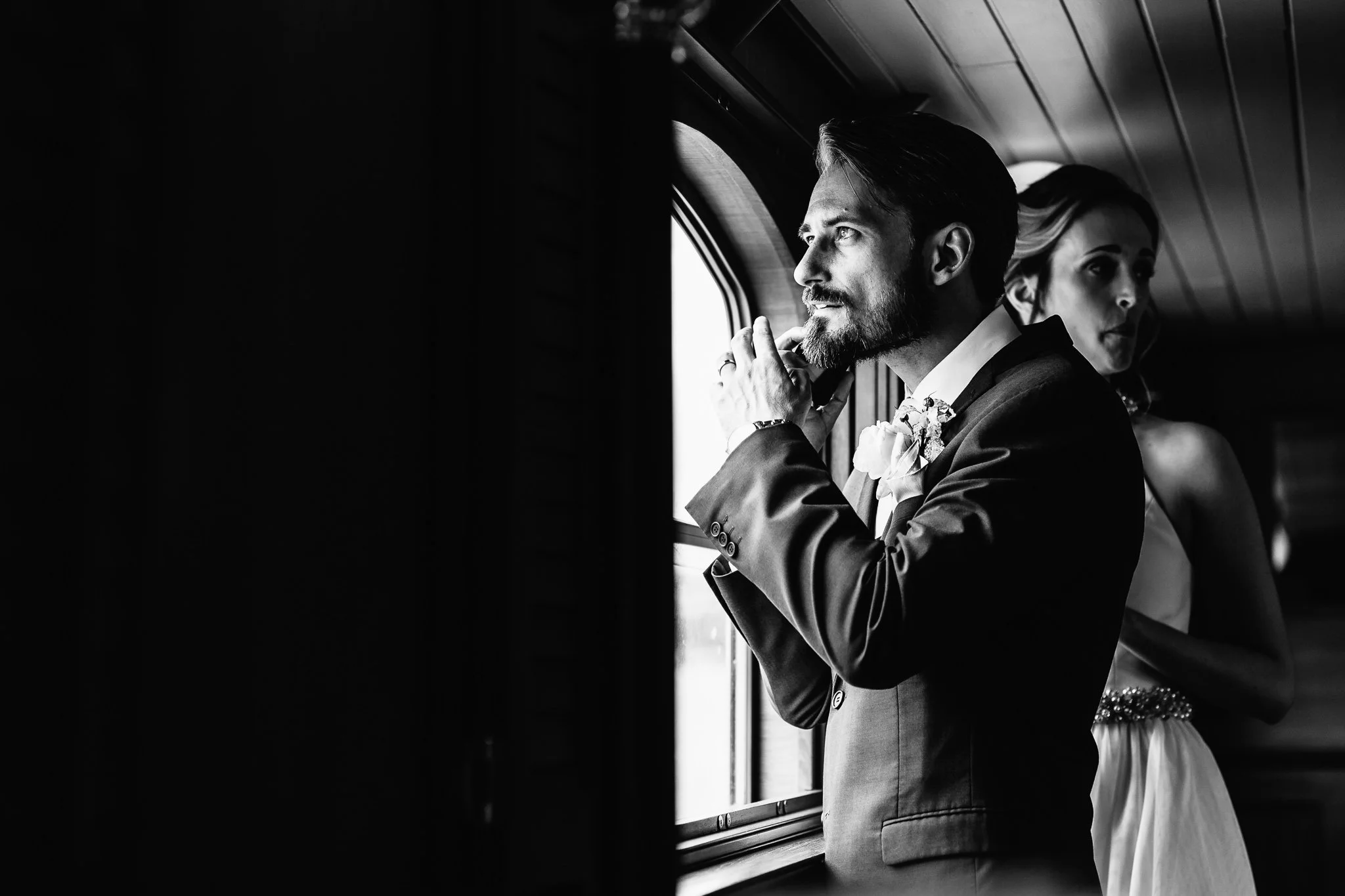  Groom looks out the window of the boat 