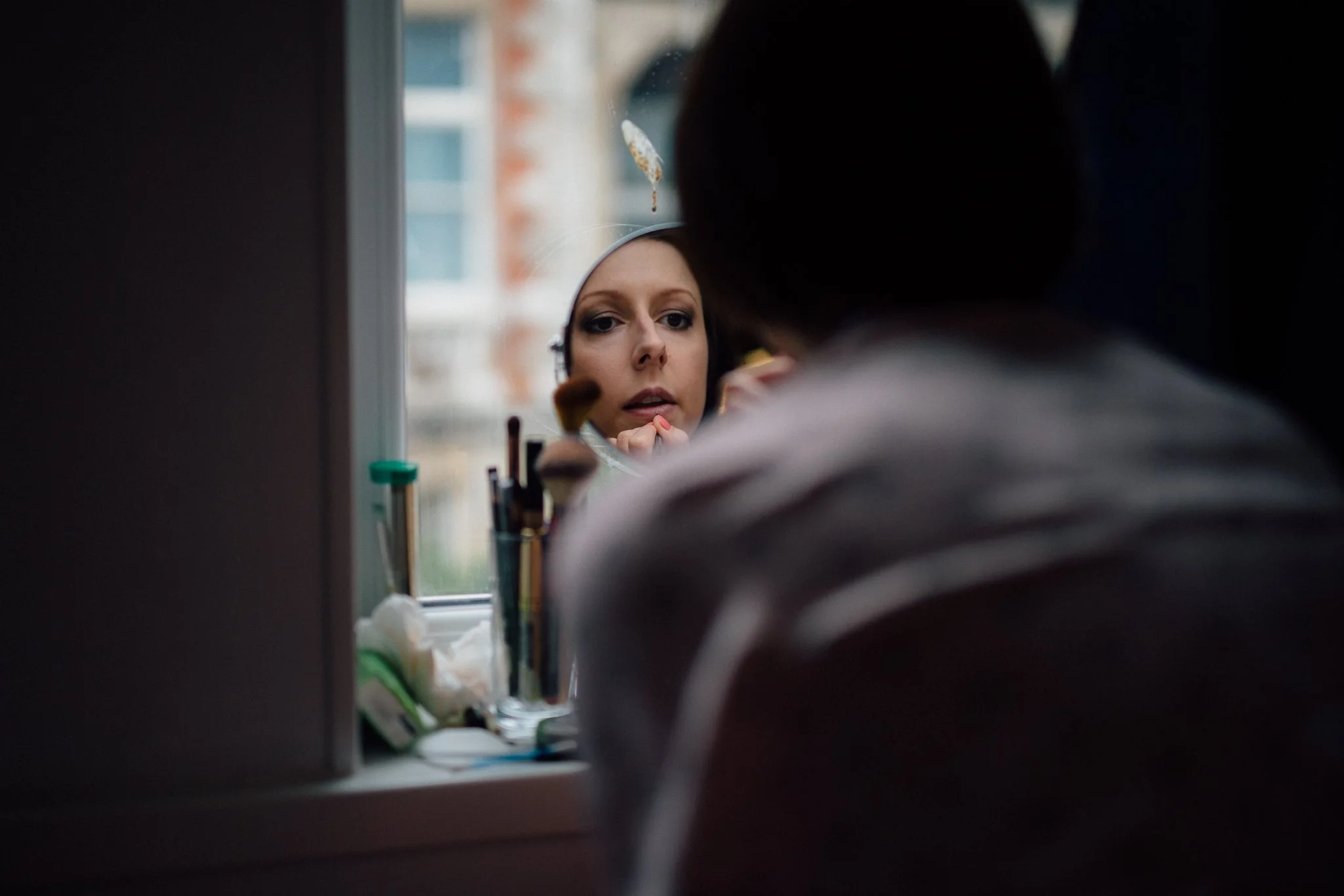  Bride applying makeup seen in reflection of mirror 