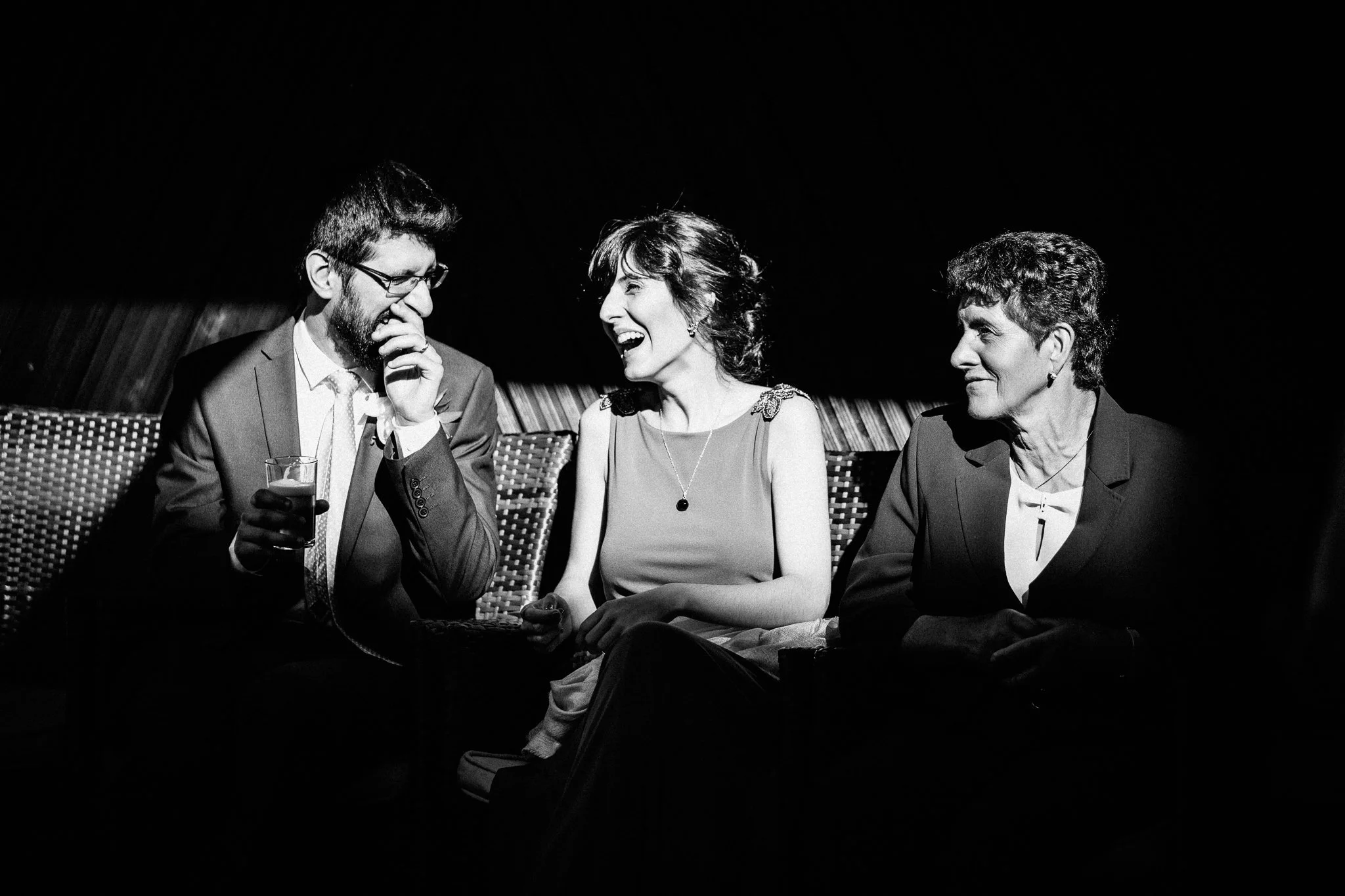  Groom, groom’s sister, and mother laugh together in the sun. 