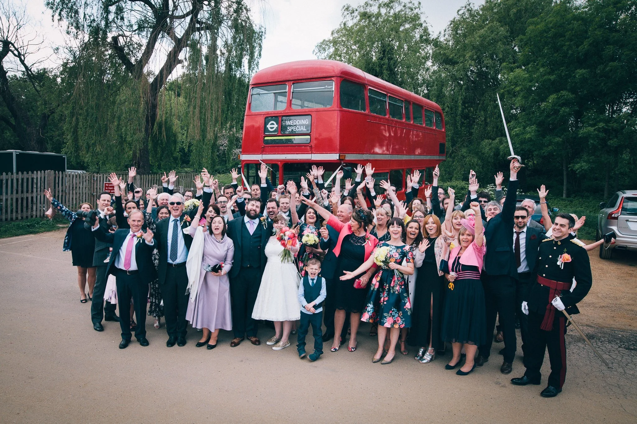  All wedding guests pose for a photo in front of a red London bus Burgh House Hampstead  