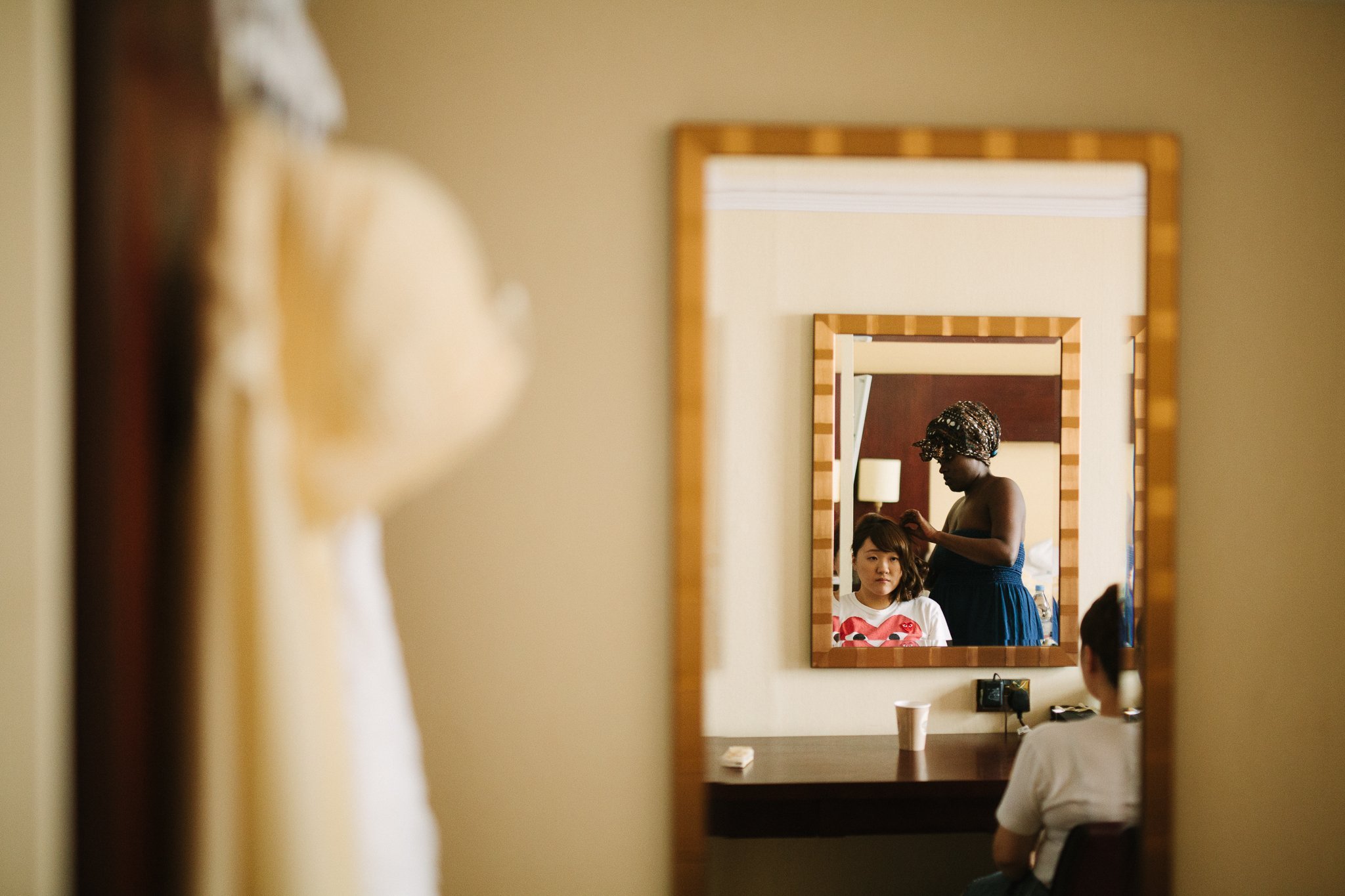  Bridesmaid having hair done looking in a mirror 
