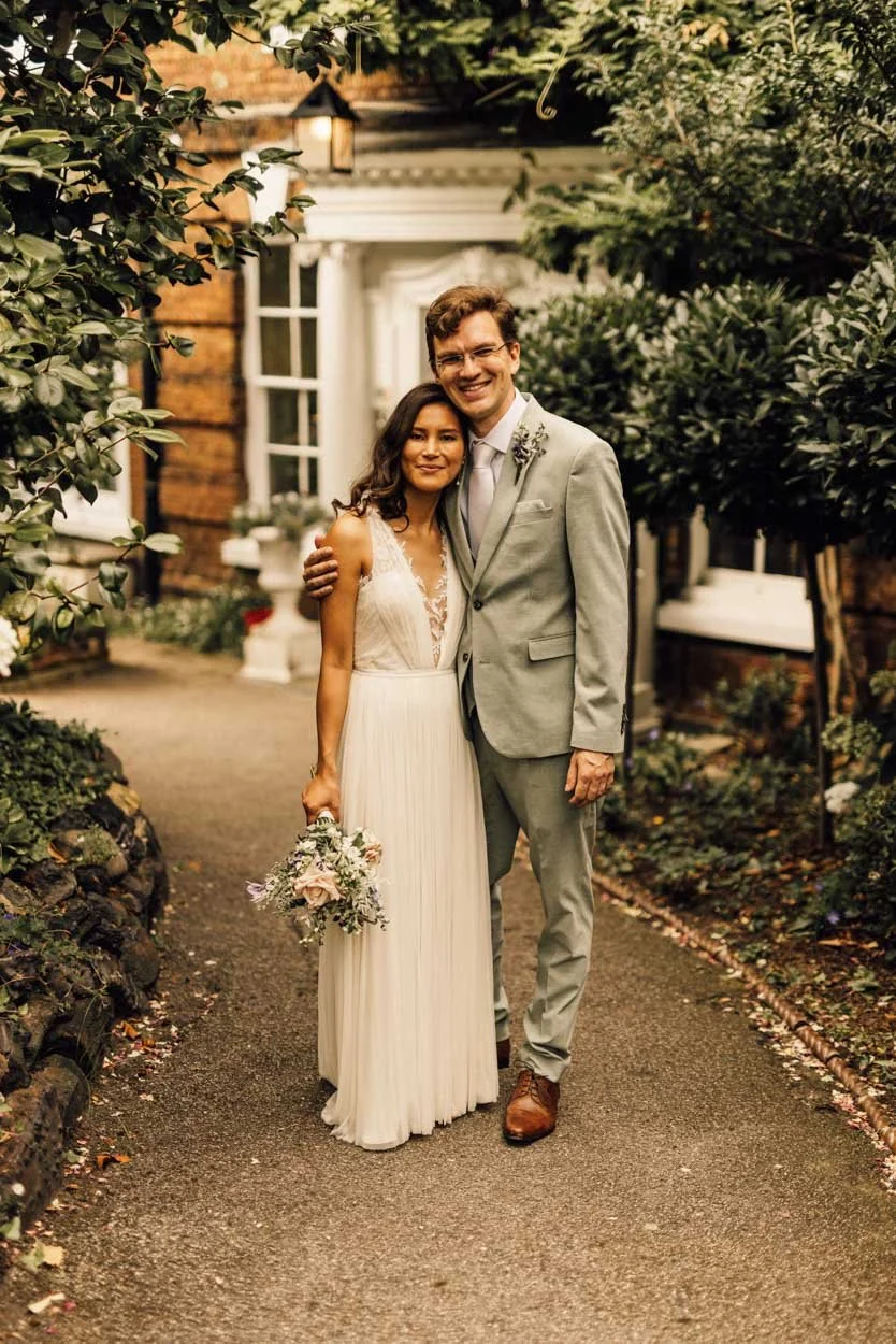 bride and groom posing outside country house with trees