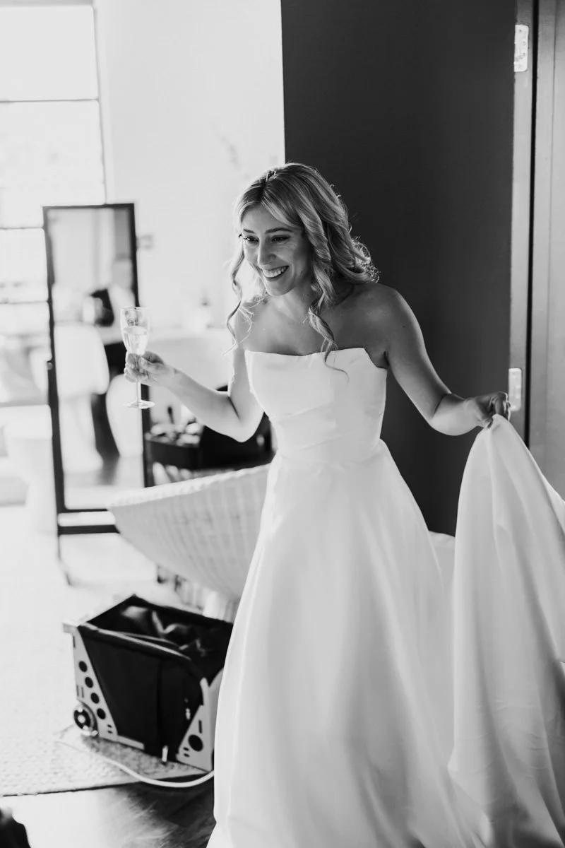 black and white photo of bride smiling holding champagne glass
