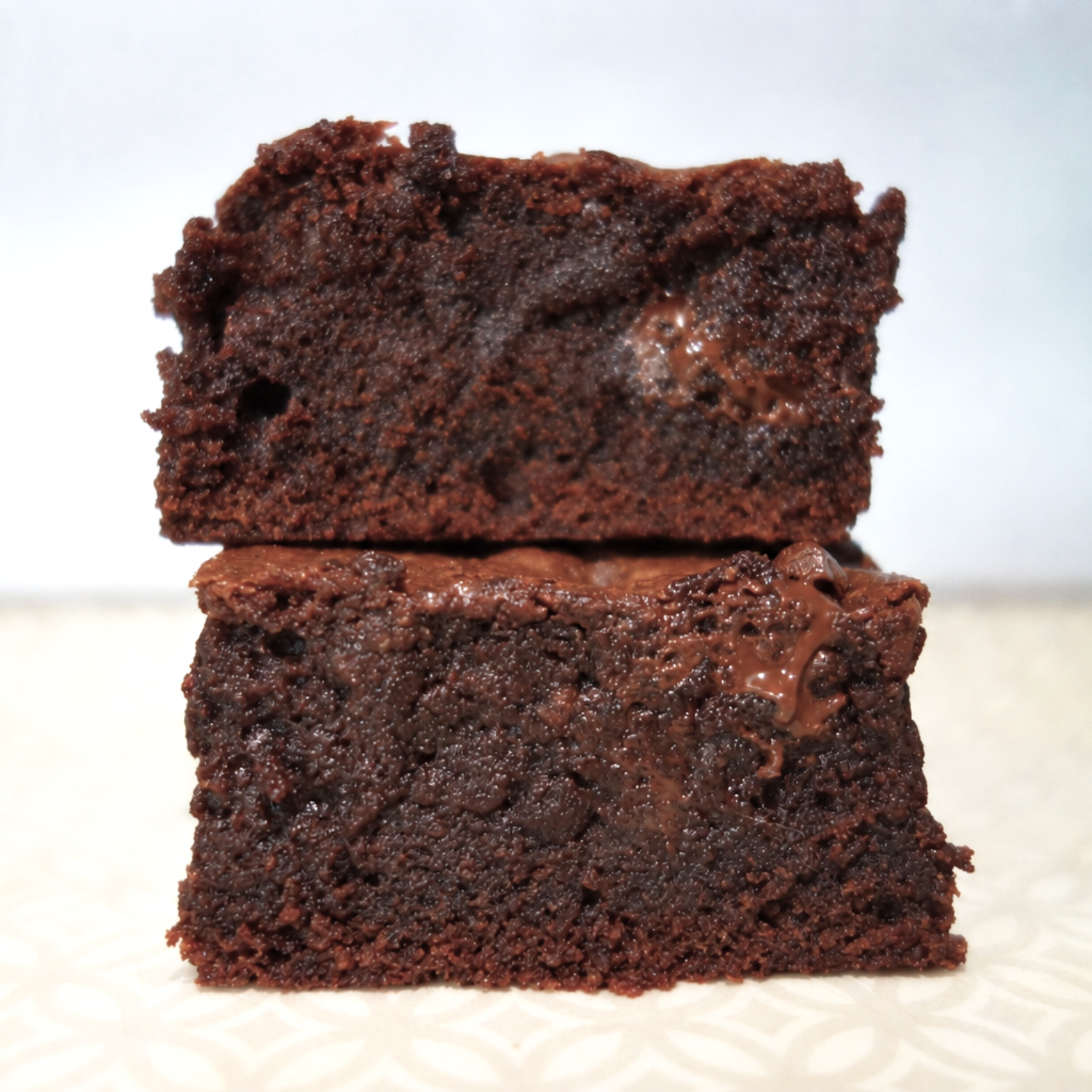 Deux morceaux de brownies au chocolat empilés, montrant une texture moelleuse et humide.