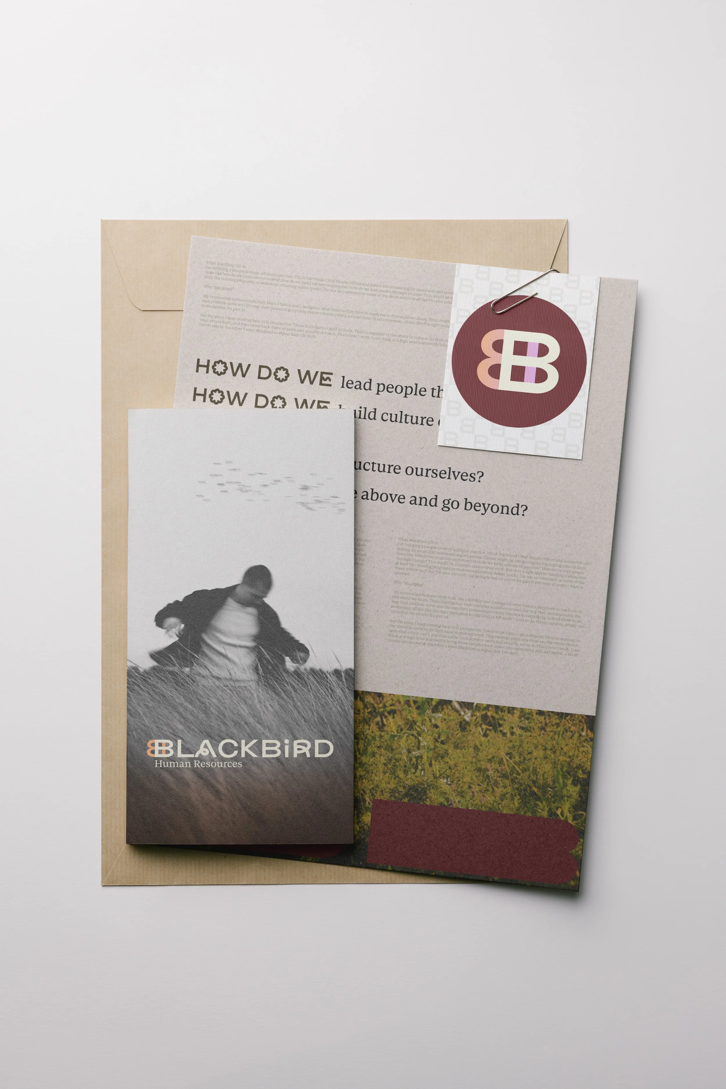 A brochure for Blackbird Human Resources features a black and white photo of a person running in a field, with a background of grass and sky. The brochure is partly covered by other printed materials, including a tag with the Blackbird logo and text.