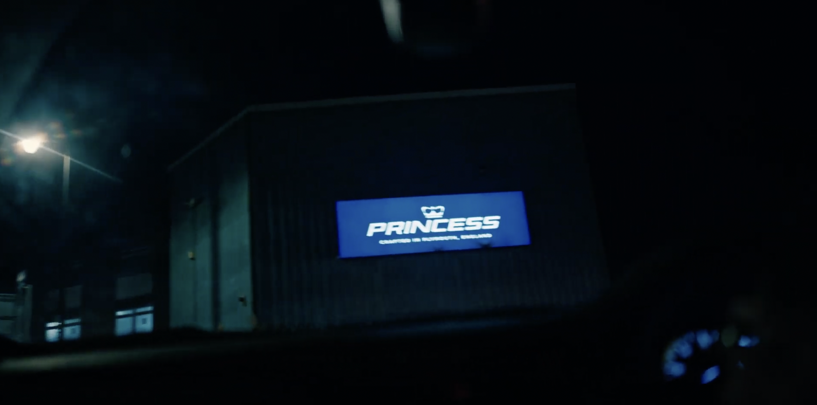 A digital sign on a building reads "PRINCESS" in white font on a blue background, with smaller text underneath that is not fully visible, taken at night.