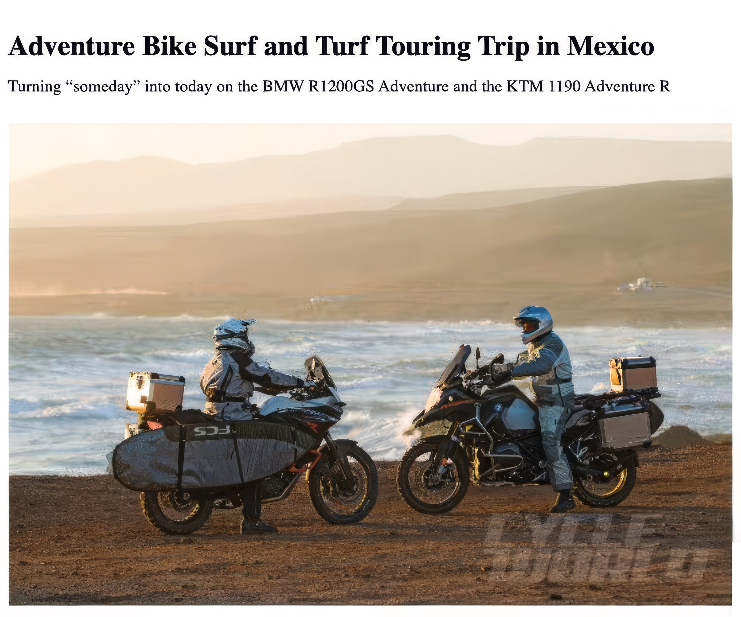 Two motorbikes equipped for adventure riding on the beach with a person standing beside one, in front of the ocean with waves and hills in the background.