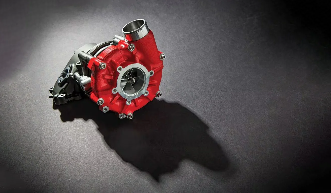 Red and silver automotive turbocharger on a dark surface with shadow.