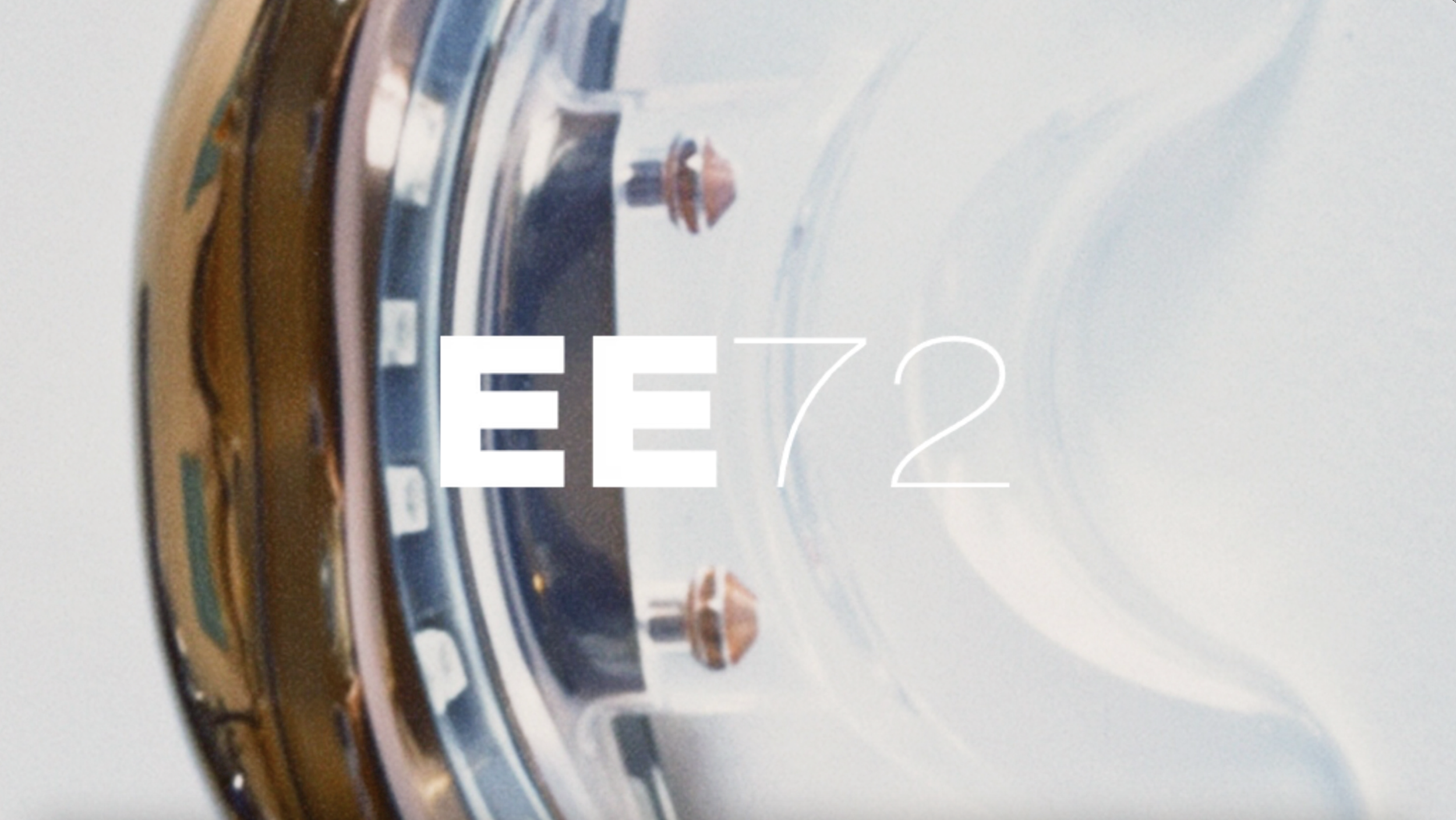 White EE72 wordmark over an abstract image of a luxury watch.