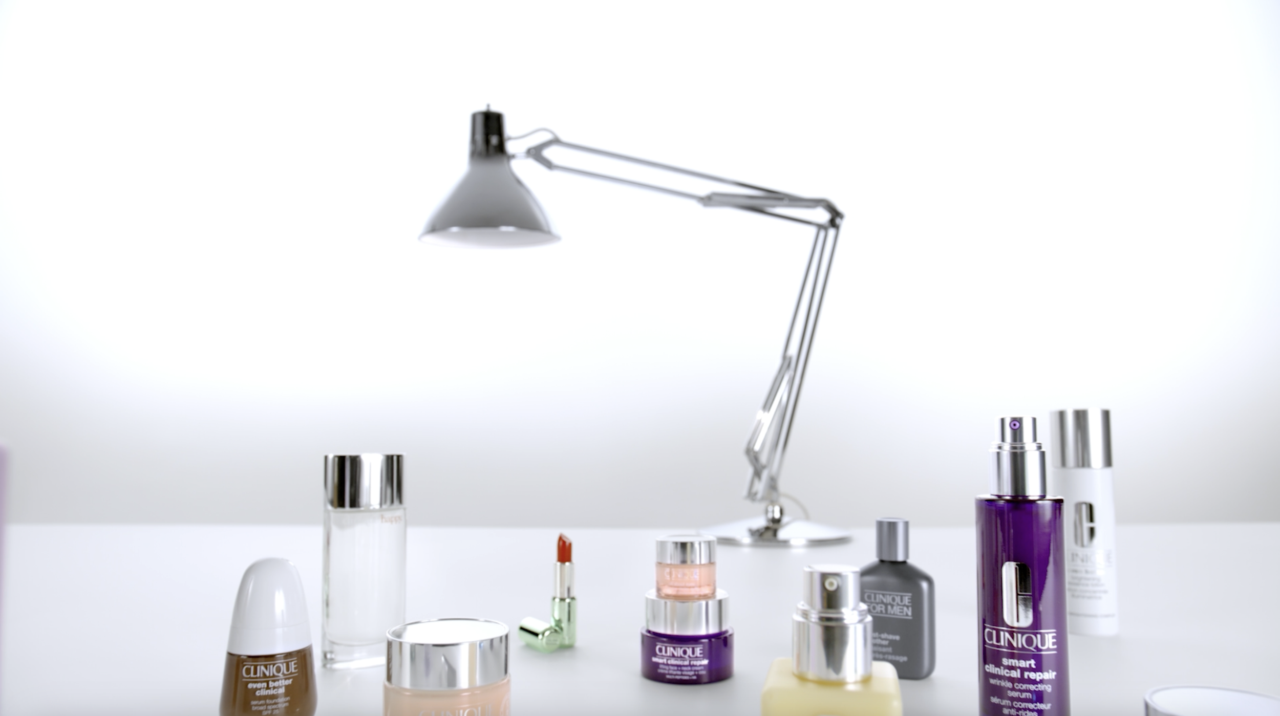 image of an assortment of clinique products on a table, being featured under a lamp.