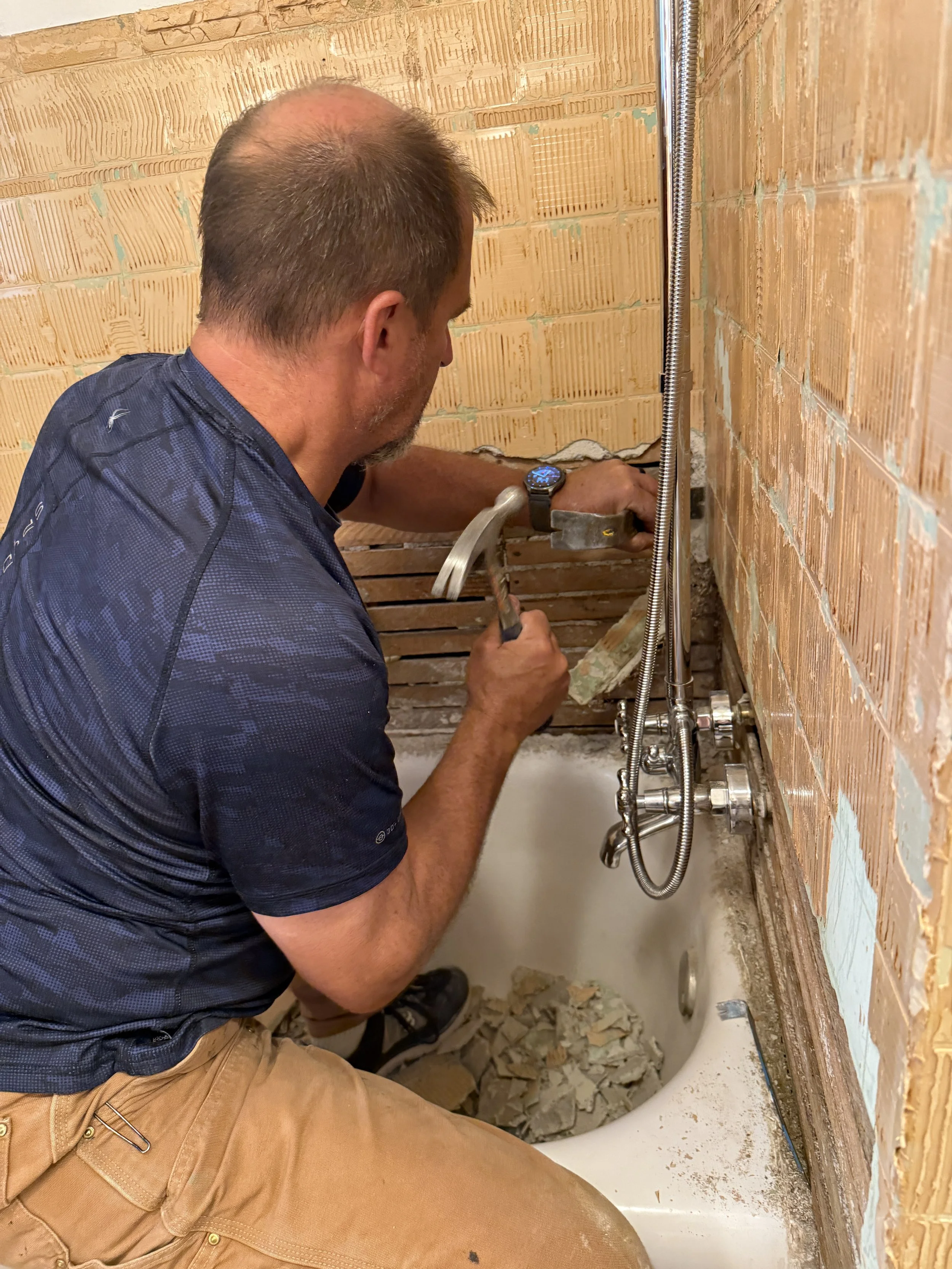 Daryl Trautmiller fixing the plumbing and doing tile work in a bathroom.