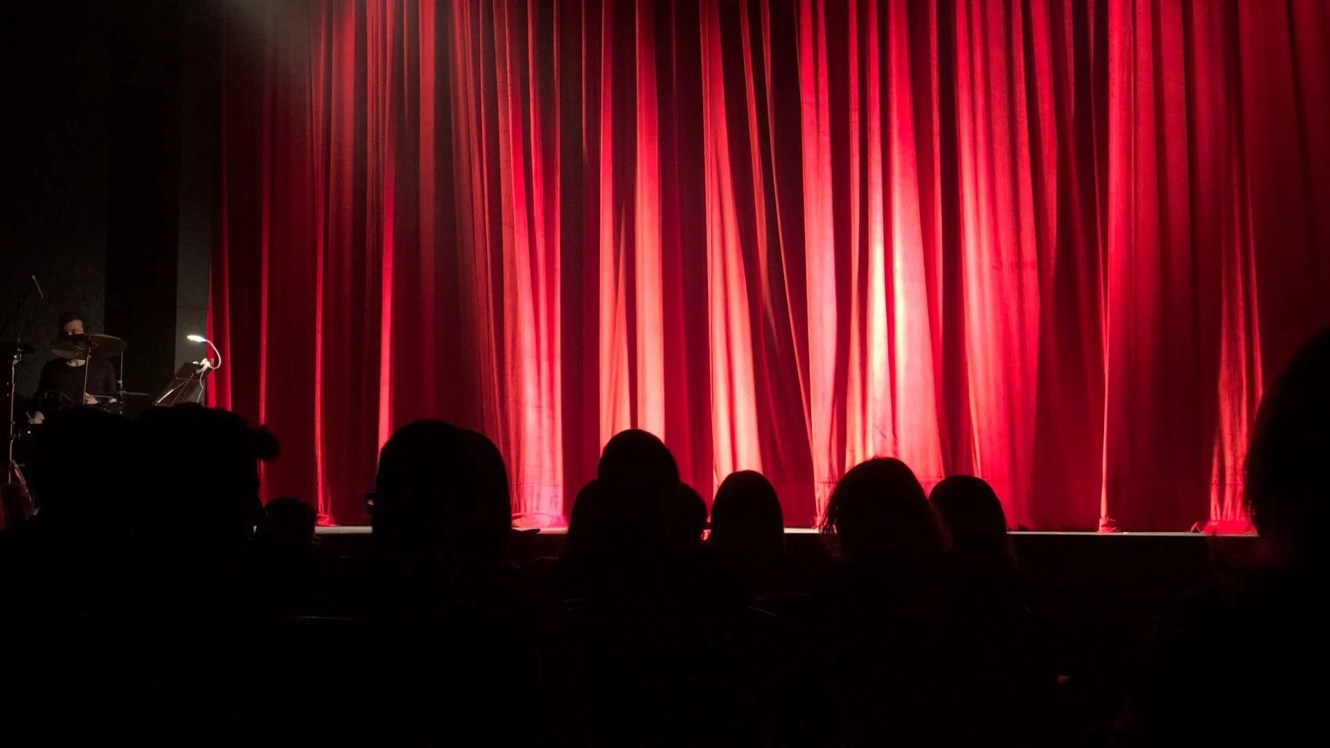 and audience waiting for a show to start with a red curtain