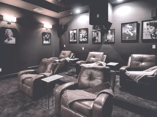 A small, dimly lit lounge with leather armchairs and framed black-and-white photographs on the wall.