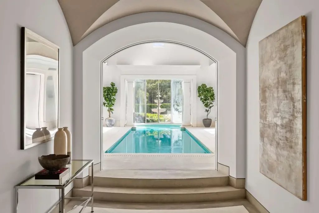 Indoor swimming pool area with large windows, potted plants, and minimalist decor.