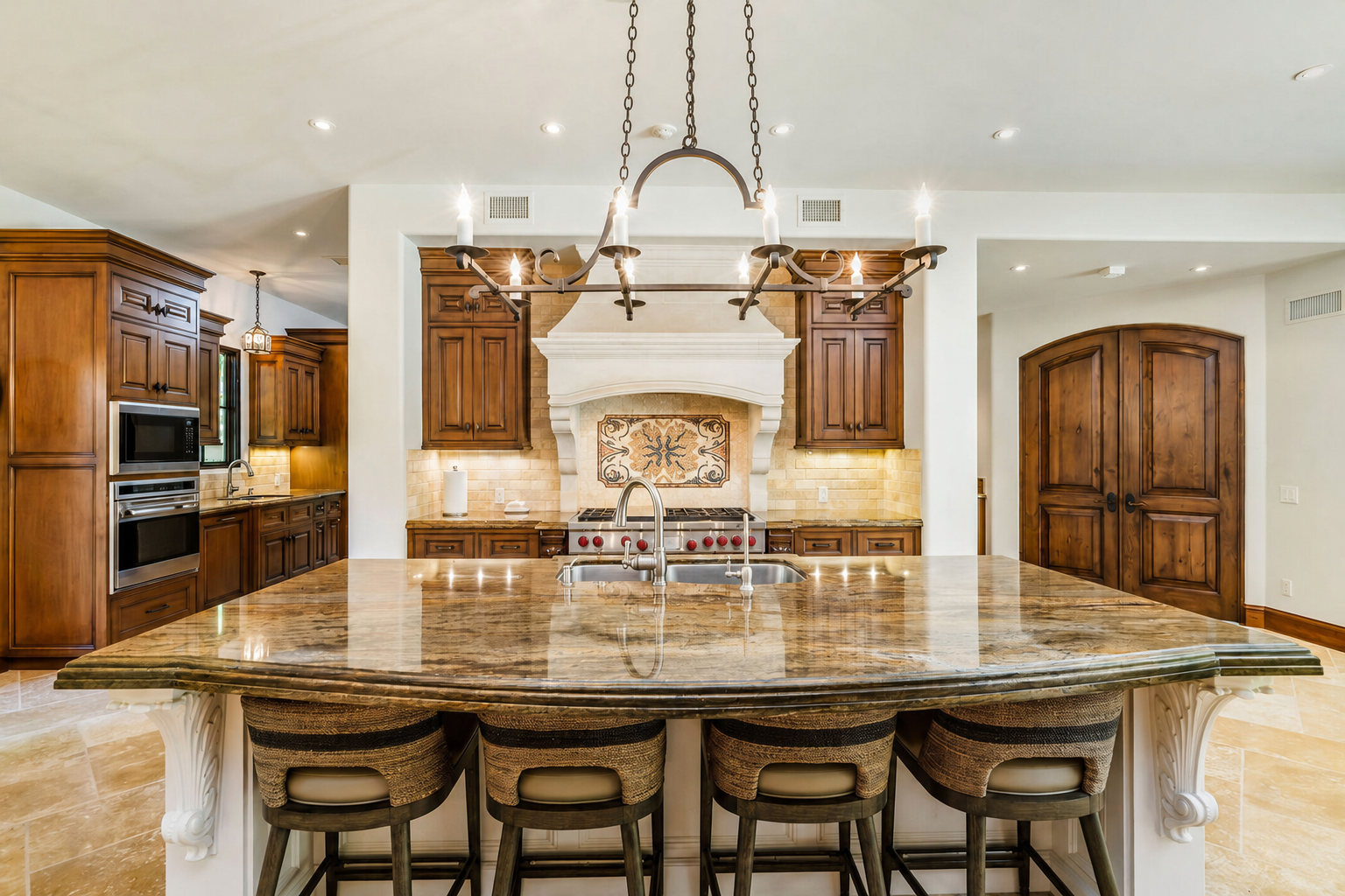 Modern kitchen with large island, wooden cabinets, and a decorative fireplace with a chandelier overhead.