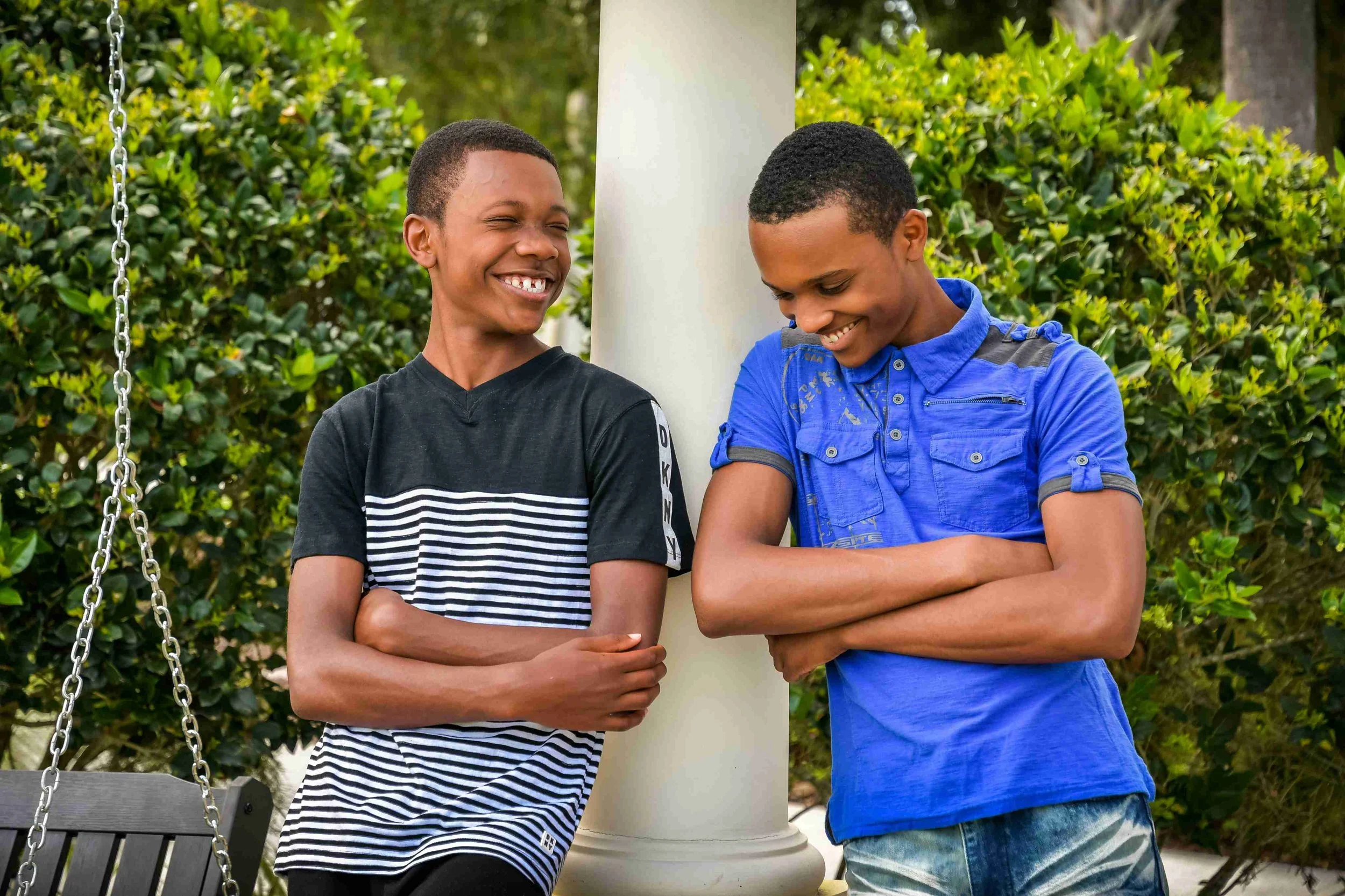 Two black teenage boys leaning against a white column and laughing-drop-shadow