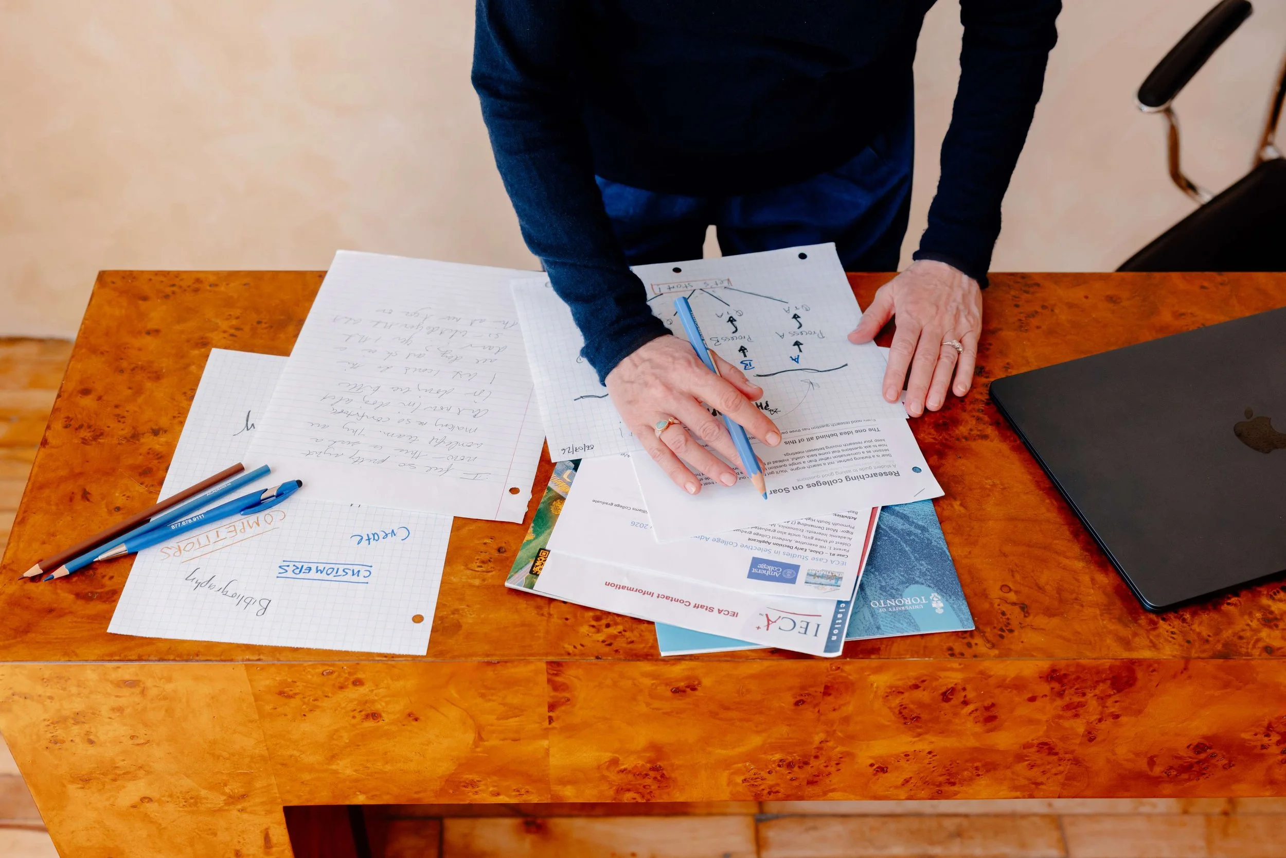 Woman's hands holding blue pencil and writing on sheets of paper on a table