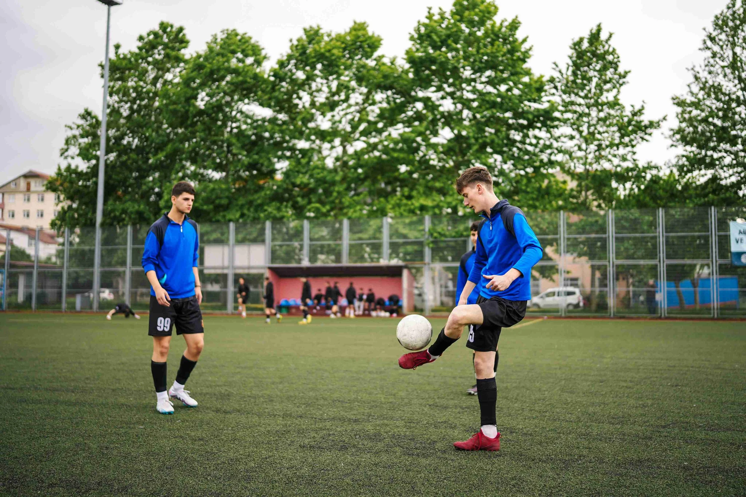 Two teenage boys in blue uniforms playing soccer-in teal card