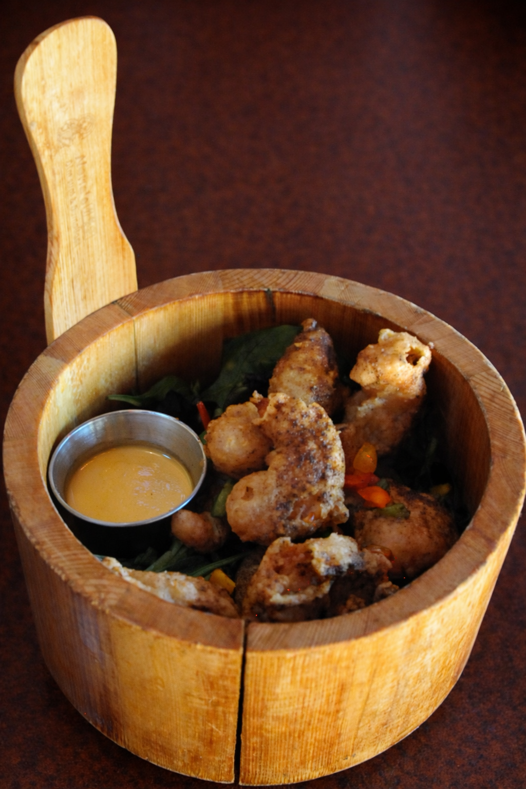 Breaded shrimp in a wood bowl with dipping sauce.