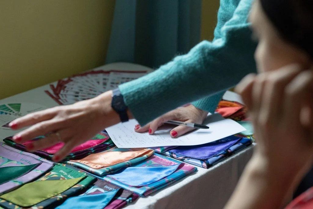 Une personne présente des échantillons de tissus colorés avec un stylo et des papiers, tandis qu'une autre personne observe attentivement.