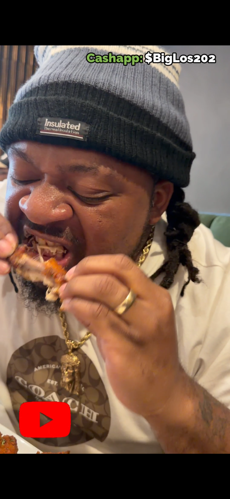 A man wearing a black beanie eating pizza at a restaurant.