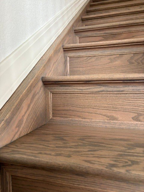 Close-up view of wooden staircase with a detailed baseboard along the wall.